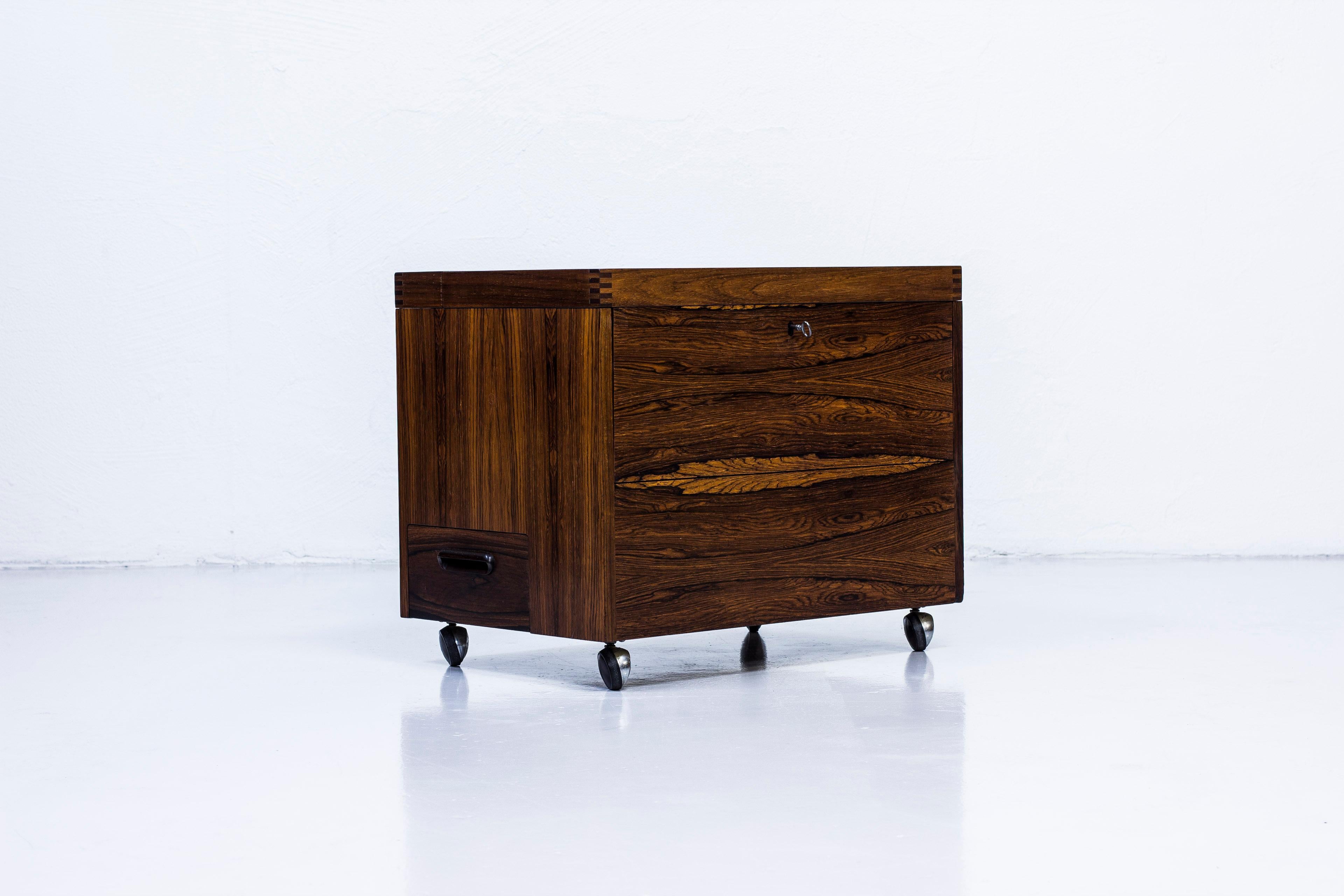 Mini bar designed by Rolf Hesland for Bruksbo tegnekontor. Produced in Norway during the 1960s by Haug Snekkeri. Made from palisander wood on both the inside and outside with brass details. Nice finger joint details on the lid. Lock in working order