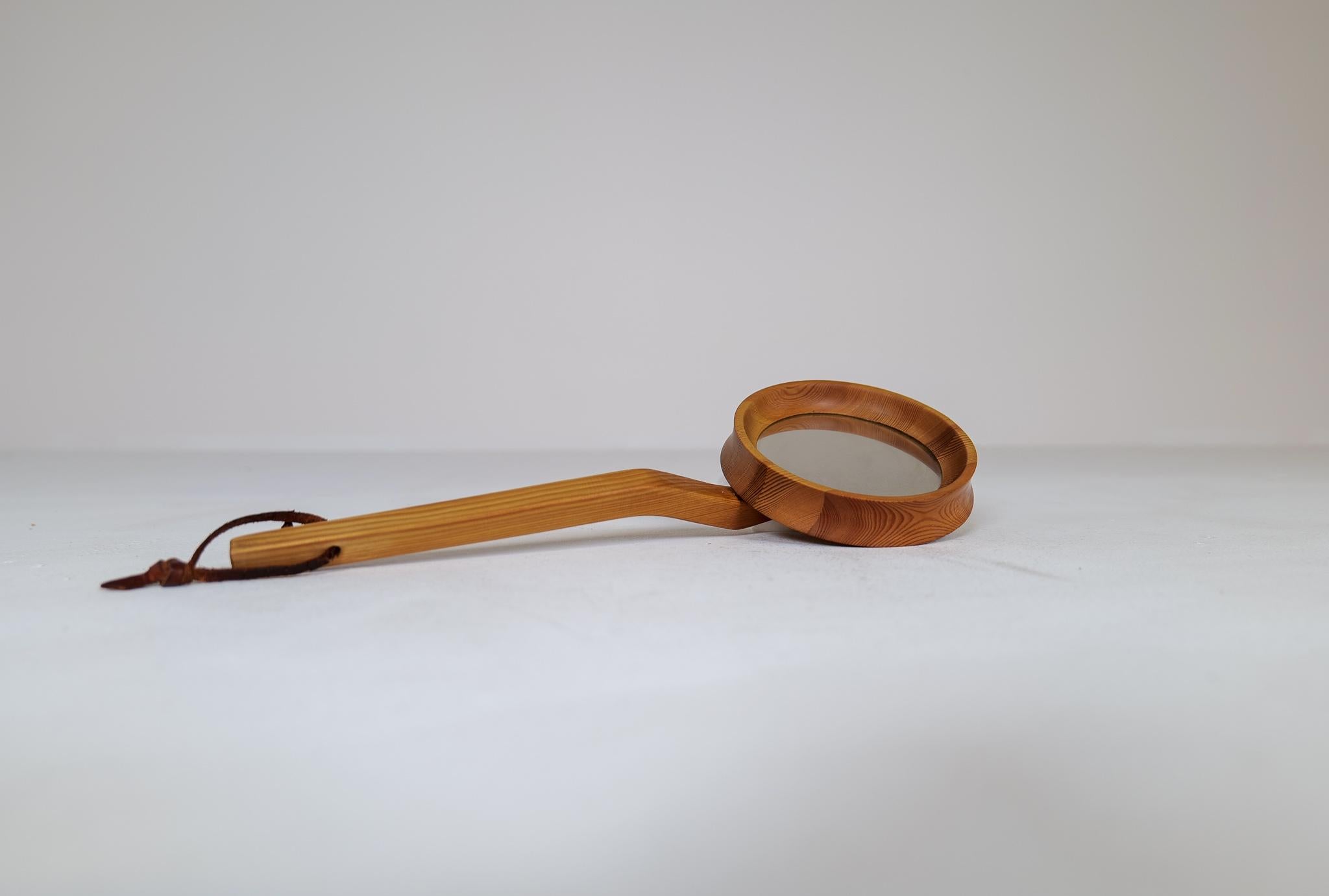 A rare hand mirror made in Pine and produced in Sweden during the 1970s. 
Slick and fine sculptured arm and mirror with leather strap.

Wear consistent with age.

Dimensions: W 33 cm Mirror diameter 10 cm Depth 5 cm.
 