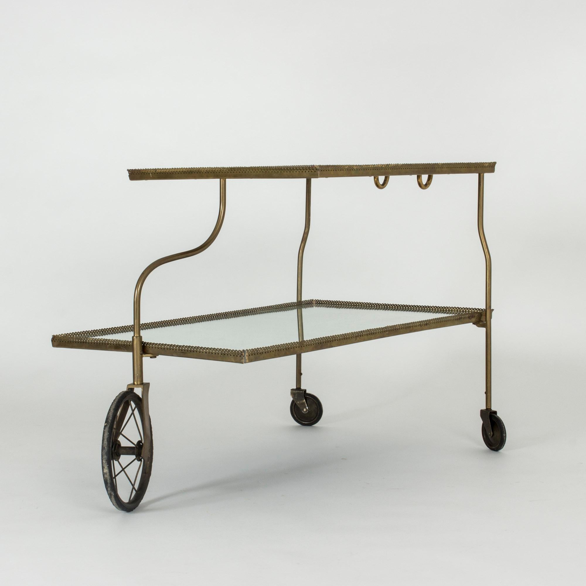 Elegant mirrored glass bar trolley on wheels by Josef Frank, made with a brass frame. The frame has a scalloped edge with a perforated pattern. Light and very decorative design.