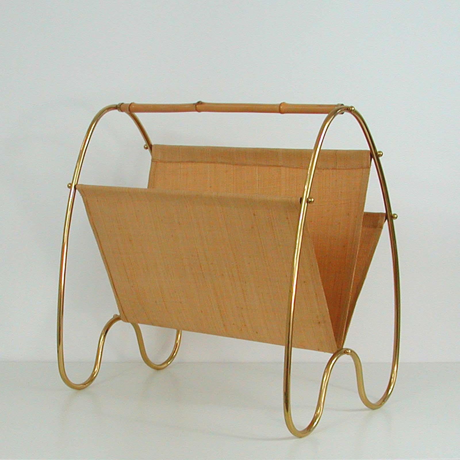This Carl Auböck style magazine rack was made in Austria in the 1950s. It features a curved brass base and a bamboo handle. The three magazine pockets are made of woven bamboo fabric. 

The rack is in very good vintage condition with minor signs of