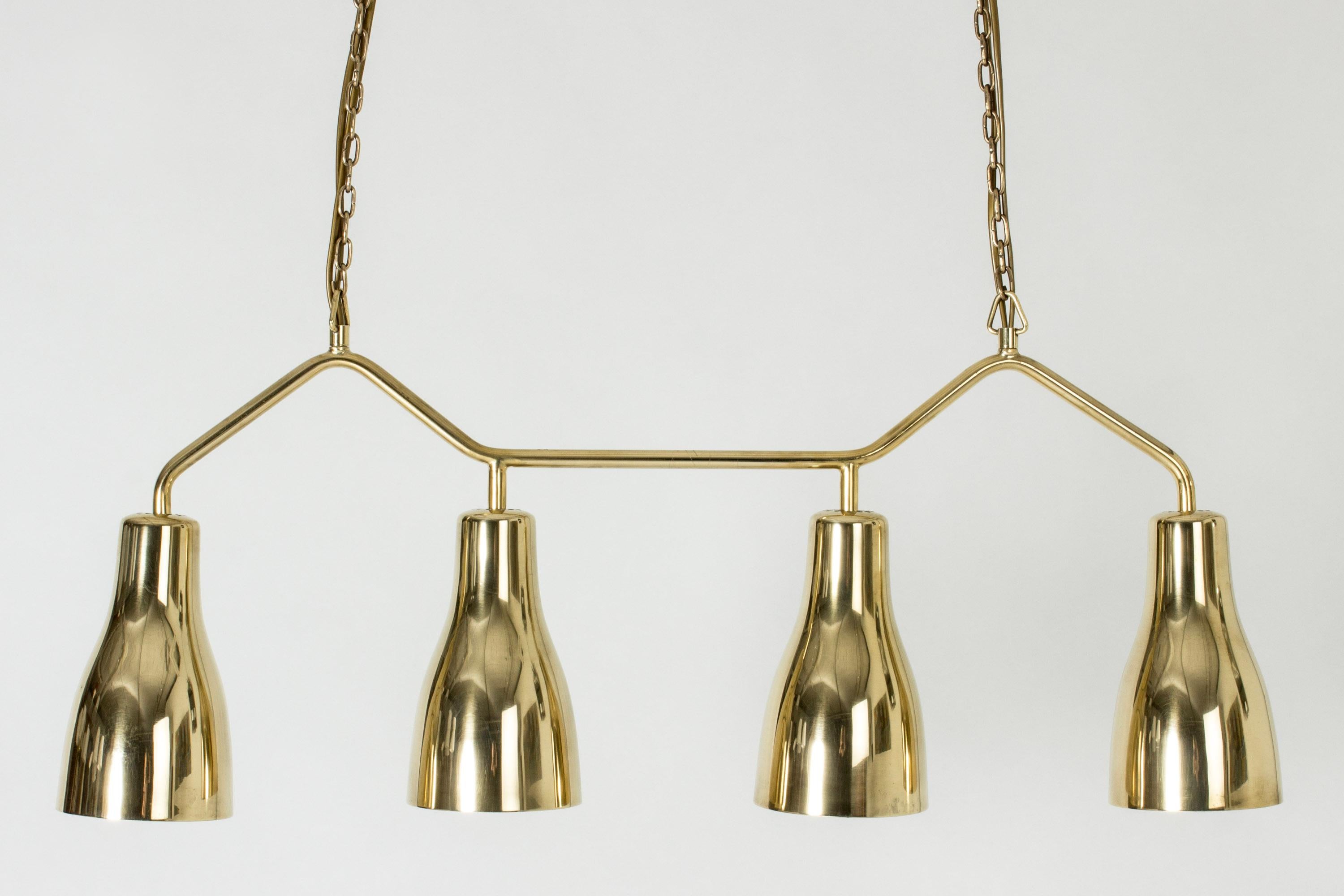Kronleuchter aus Messing von Hans Bergström, in schlichtem Design mit vier aufeinander abgestimmten Lampenschirmen. Aufgehängt an einer Kette, die in der Länge verstellbar ist, bis zu 187 cm. Die Leuchte ist perfekt für eine Küchentheke oder