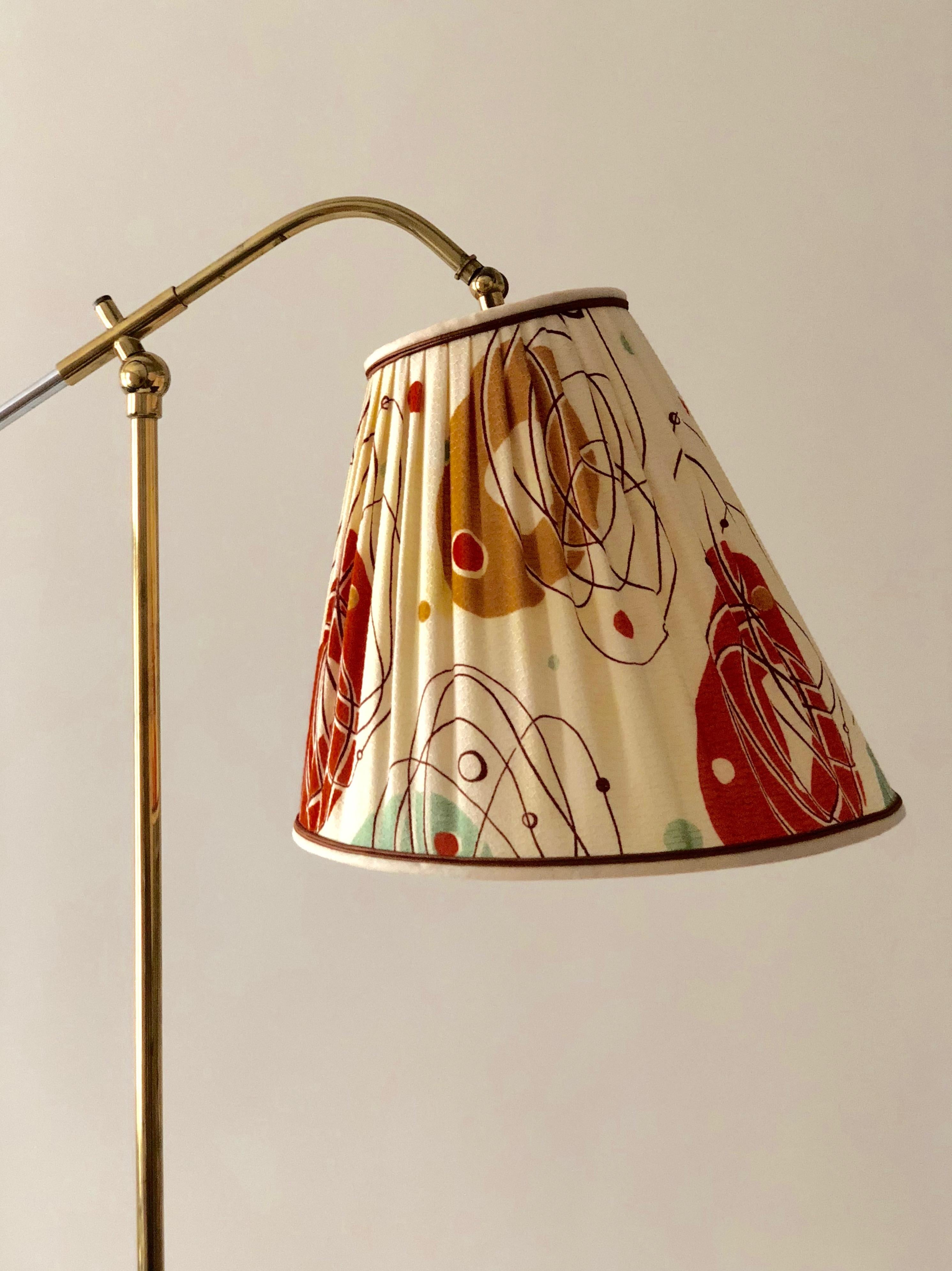 This midcentury, brass floor lamp from Rupert Nikoll was made in the 1950s. It is full of details, such as the cone shaped foot, the swivel joint
at the top of the column for tilting the lamp, an additional swivel joint at the top of the shade for