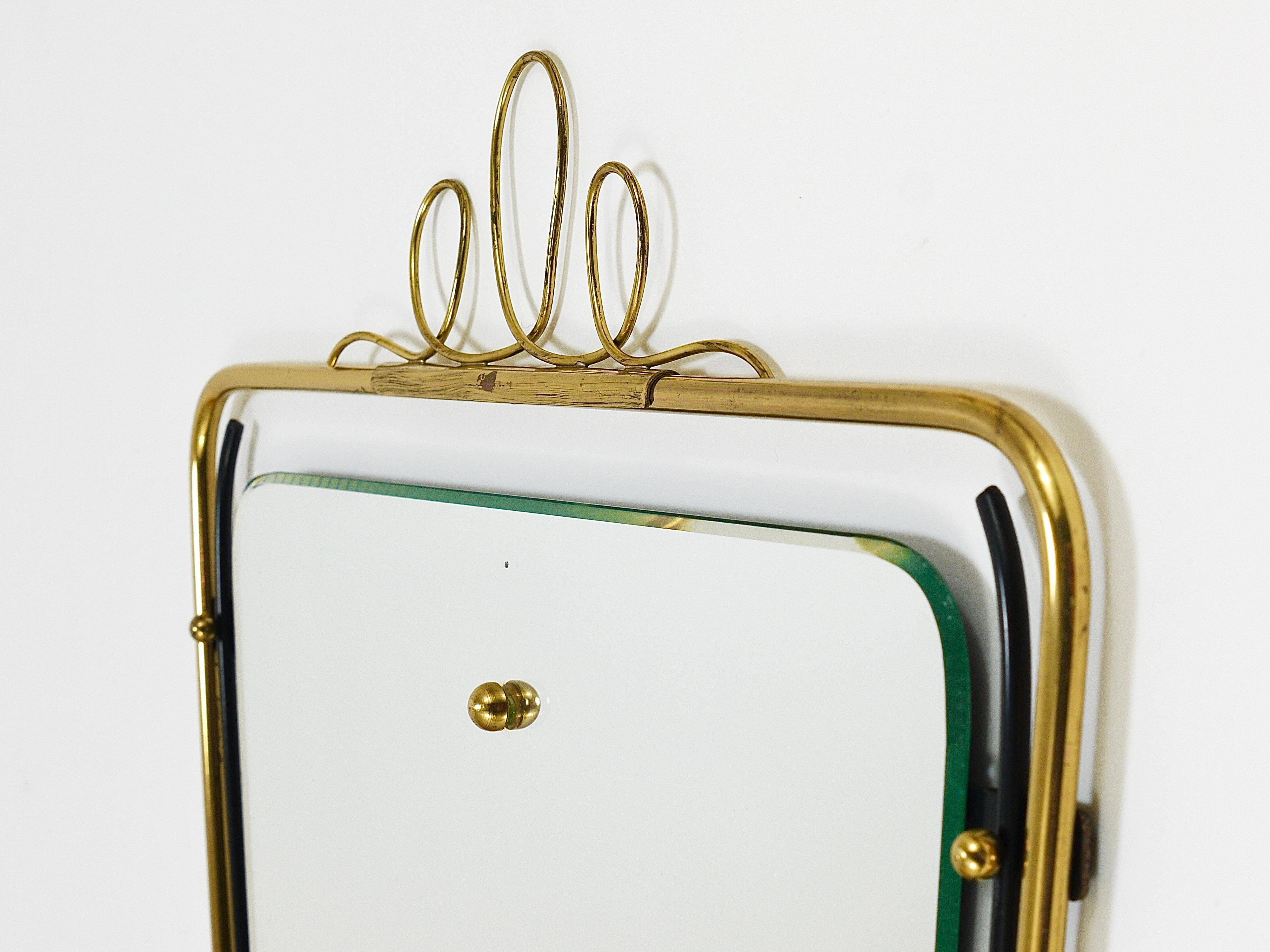 A lovely square Italian midcentury vintage brass loop wall mirror from the 1950s. Its frame is made of black metal and brass with a charming decorative crown on its top and other beautiful brass details. In very good condition with marginal patina