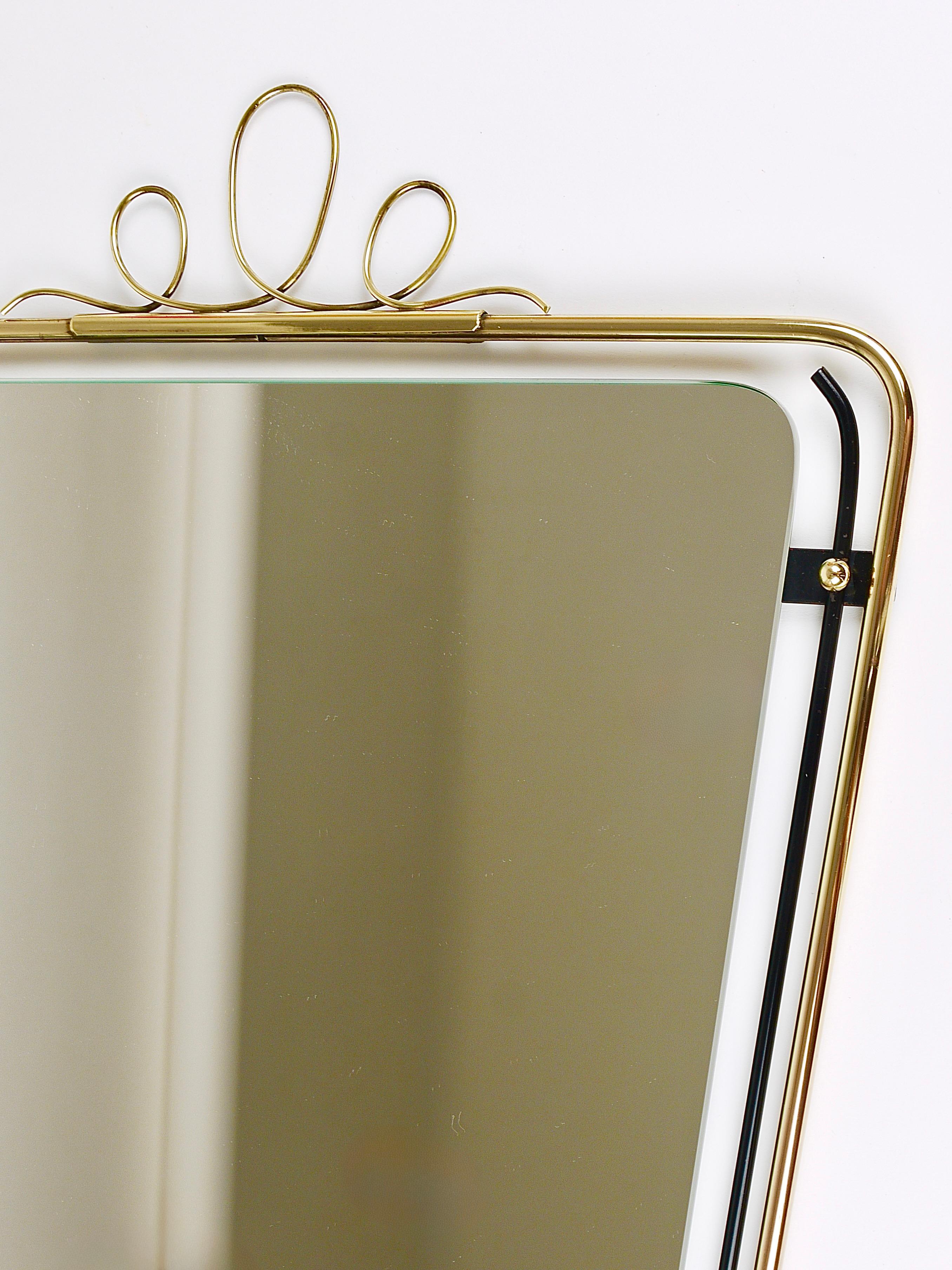 A lovely square elegant and beautifully proportioned Italian midcentury vintage brass loop wall mirror from the 1950s. Its frame is made of black metal and brass with a charming decorative crown on its top and other beautiful brass details. It has a