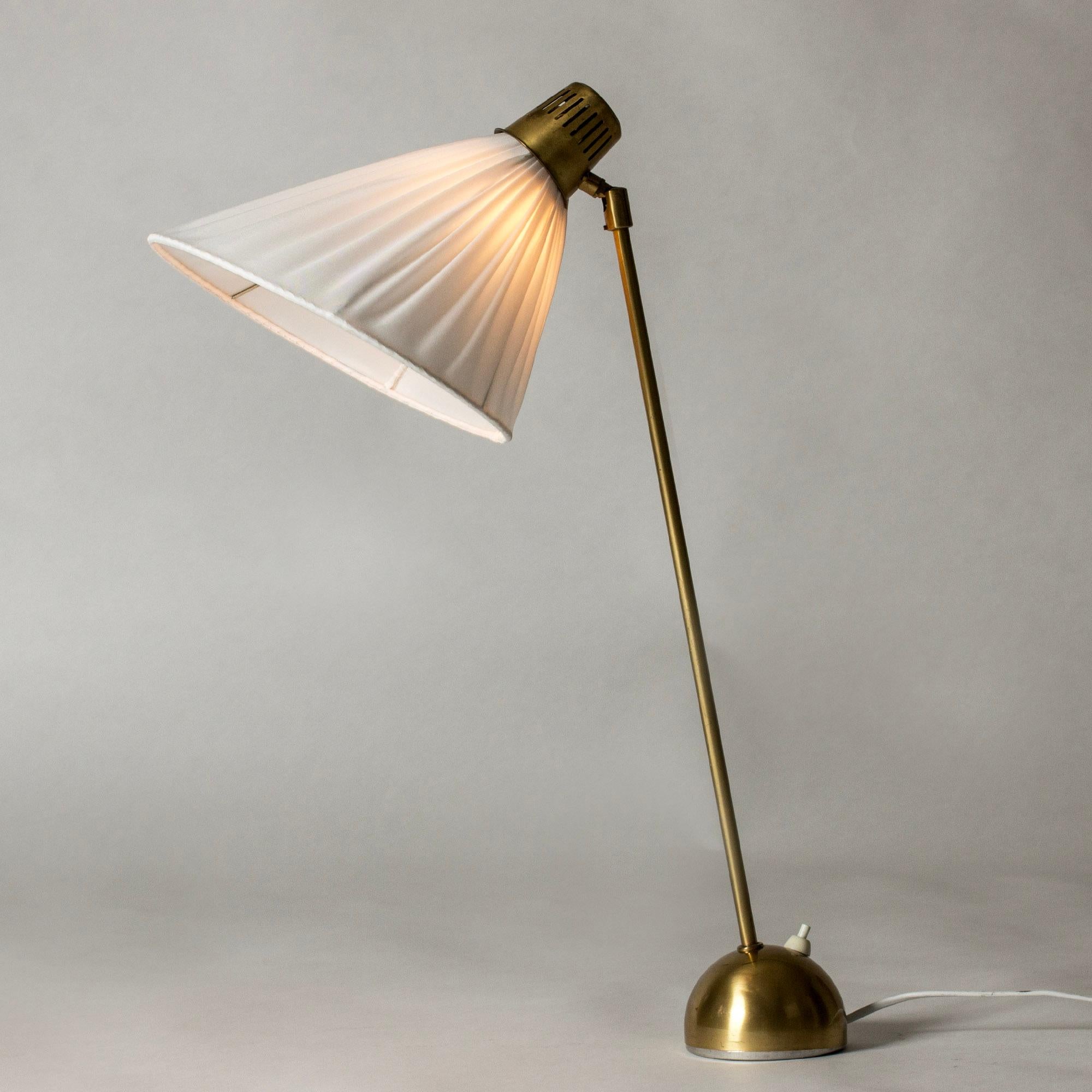 Élégante lampe de table ou de bureau en laiton de Hans Bergström avec une tige allongée et un abat-jour réglable. Base arrondie, belle silhouette.