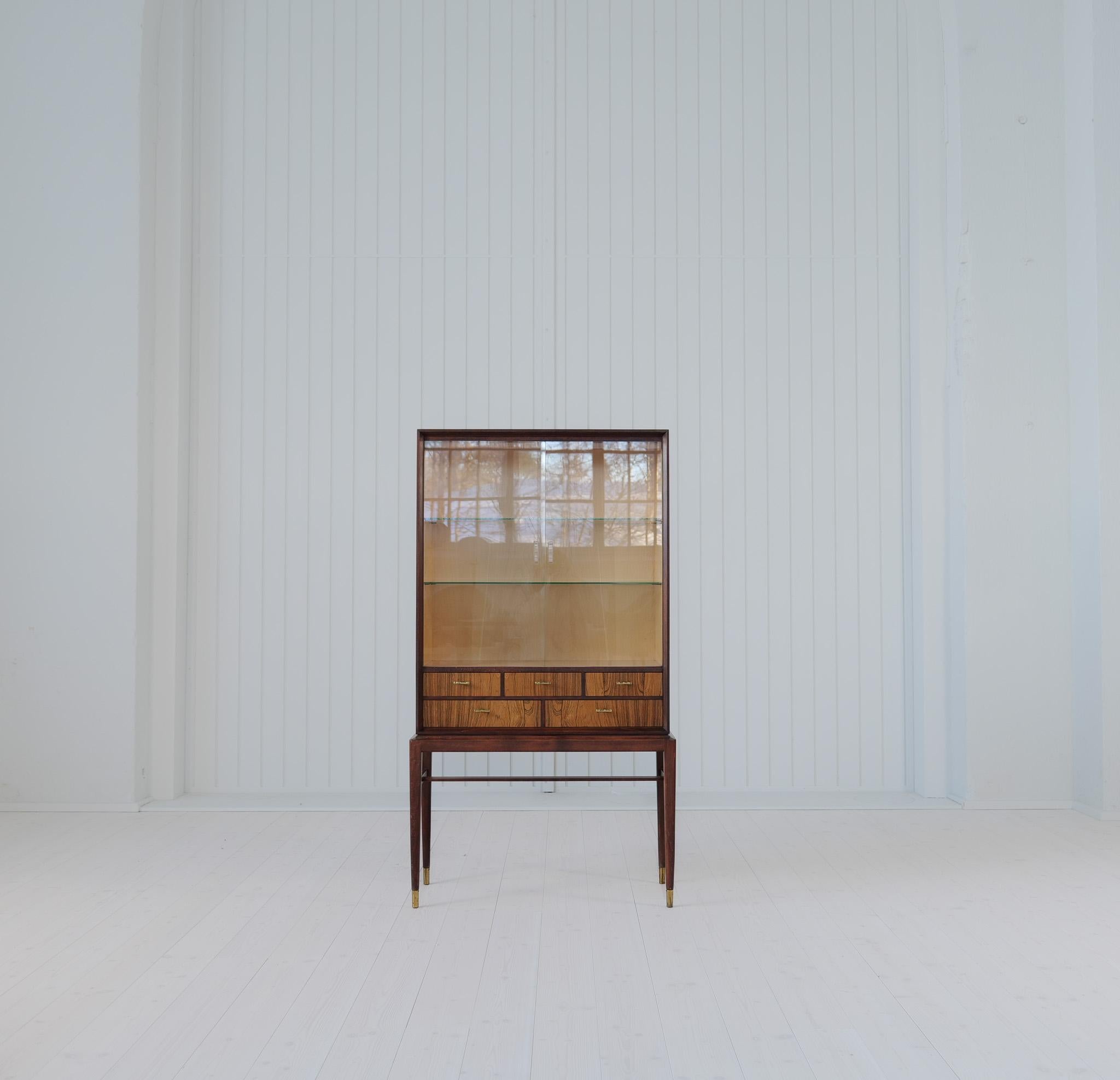 This beautiful cabinet was designed by Svante Skogh for Seffle Möbelfabrik, circa 1959 in Sweden.
This piece features a rosewood and teak frame with two large sliding glass doors and five drawers with handles in brass.

Condition: Good vintage
