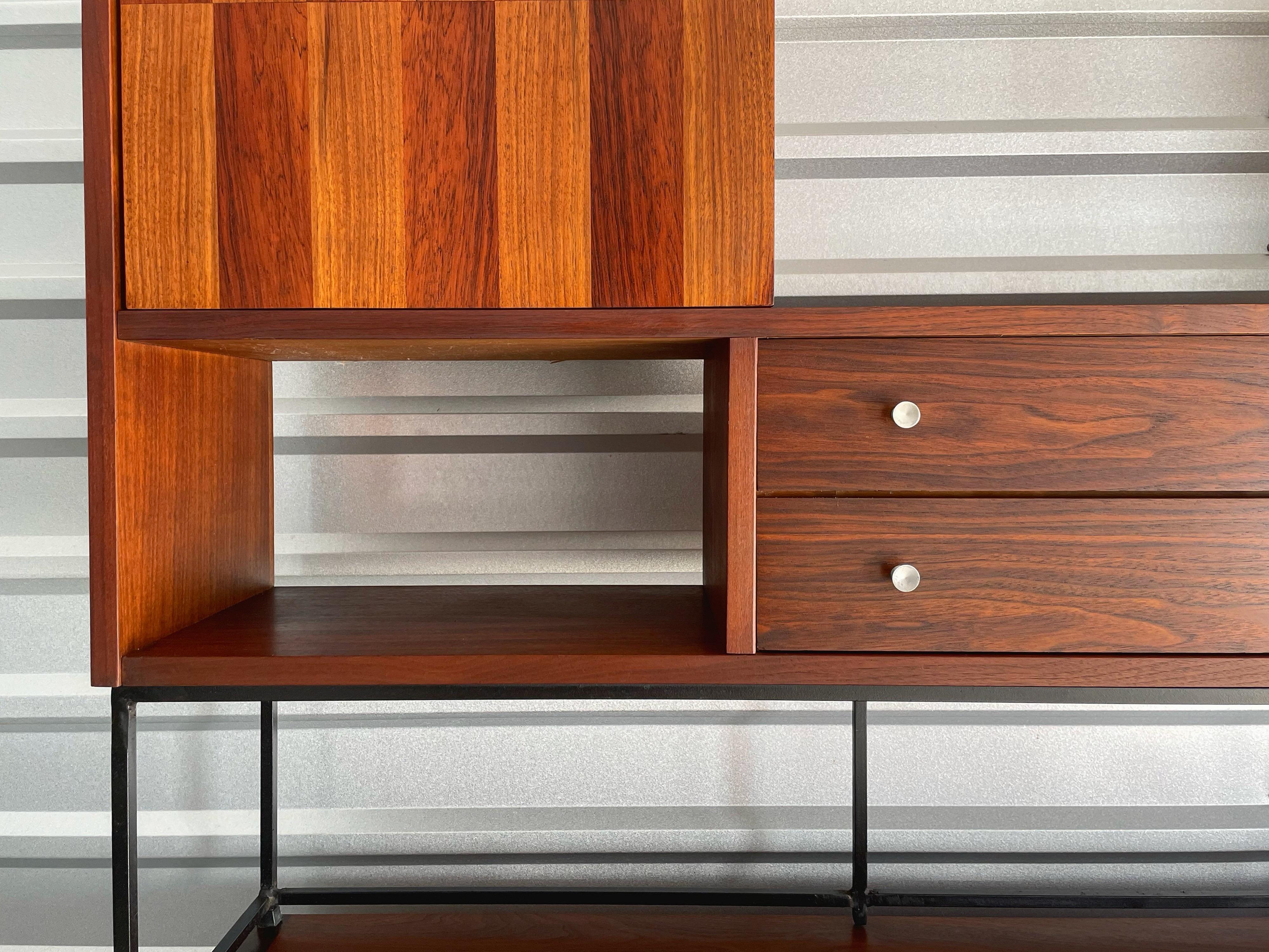 Monumental two-piece Mid-Century Modern credenza and hutch top designed by H. Paul Browning and produced by Stanley. Walnut cases with rosewood inlay and brushed aluminum pulls. Hutch top rests on a wrought iron base. Adjustable shelved space on the