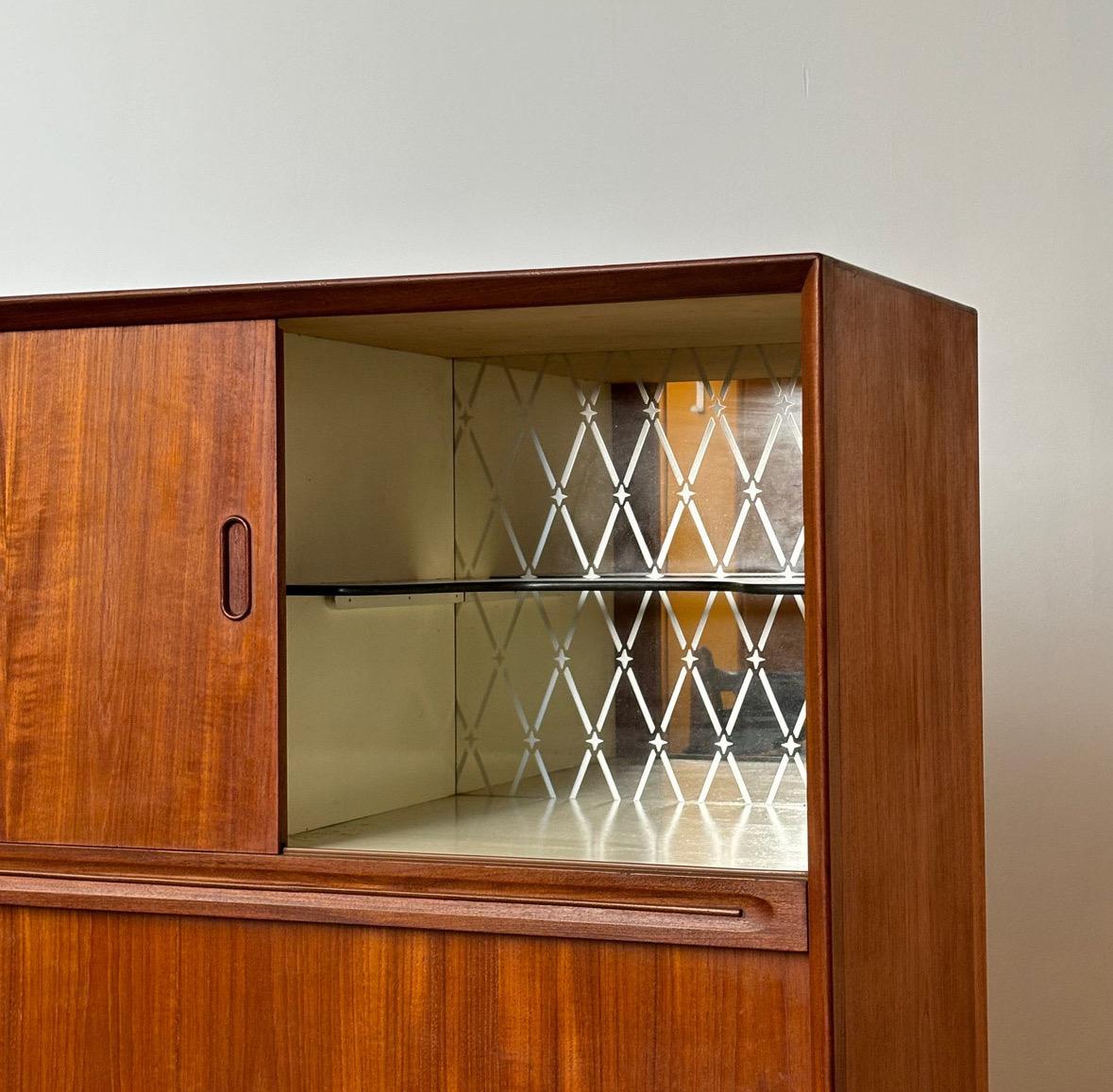 La credenza alta danese di metà secolo, prodotta da Genega Møbler nella Danimarca degli anni '60, esemplifica l'eleganza e la funzionalità del design di metà secolo. Dotata di una base in rovere massiccio, la credenza vanta sottili elementi di