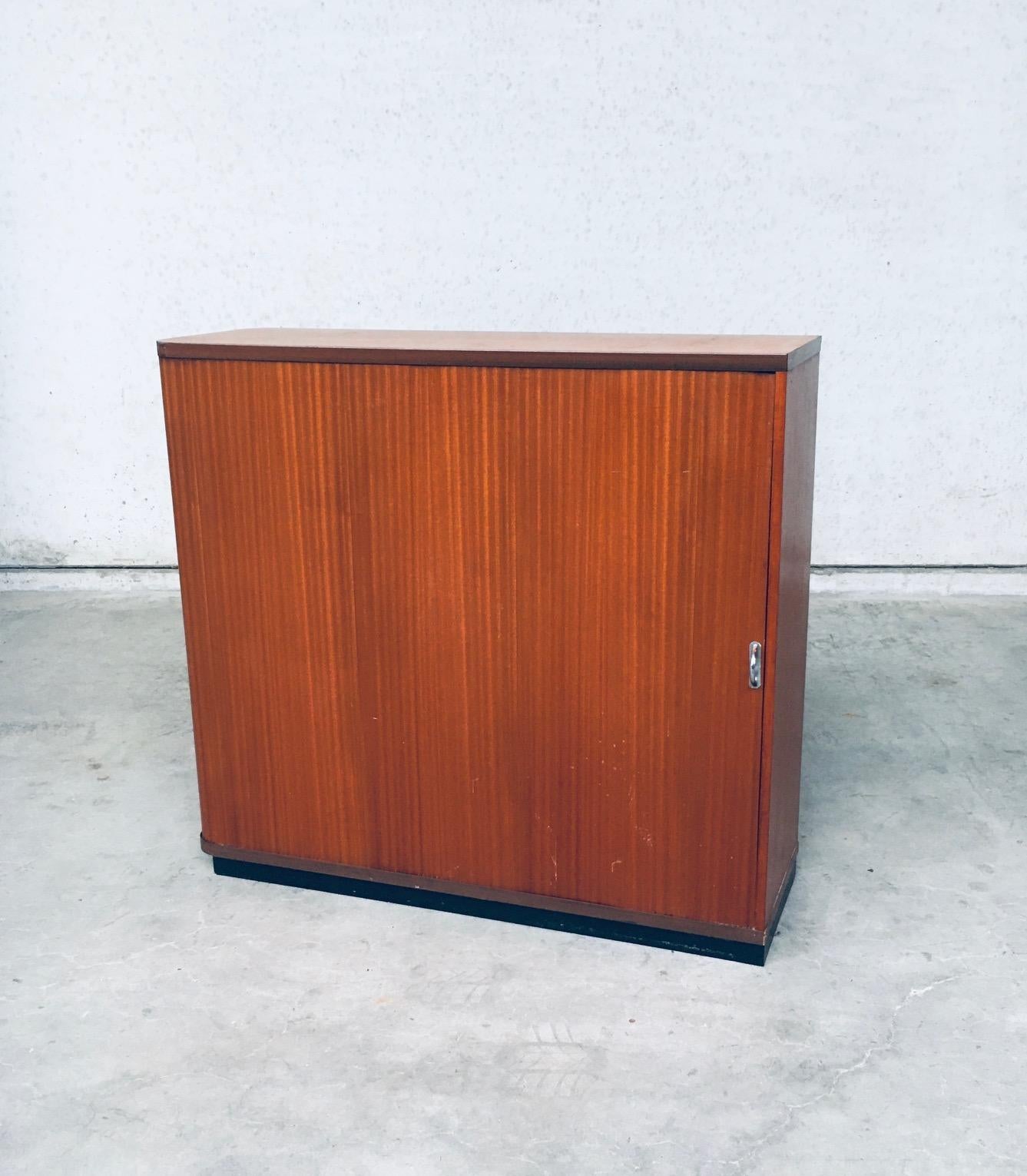 Vintage Mid-Century Modern design sliding door filing cabinet, made in Belgium 1960s. Wood with wood veneer constructed cabinet with a sliding door that slides all the way open to the back. Has 2 shelves. Comes in good overal condition, with good