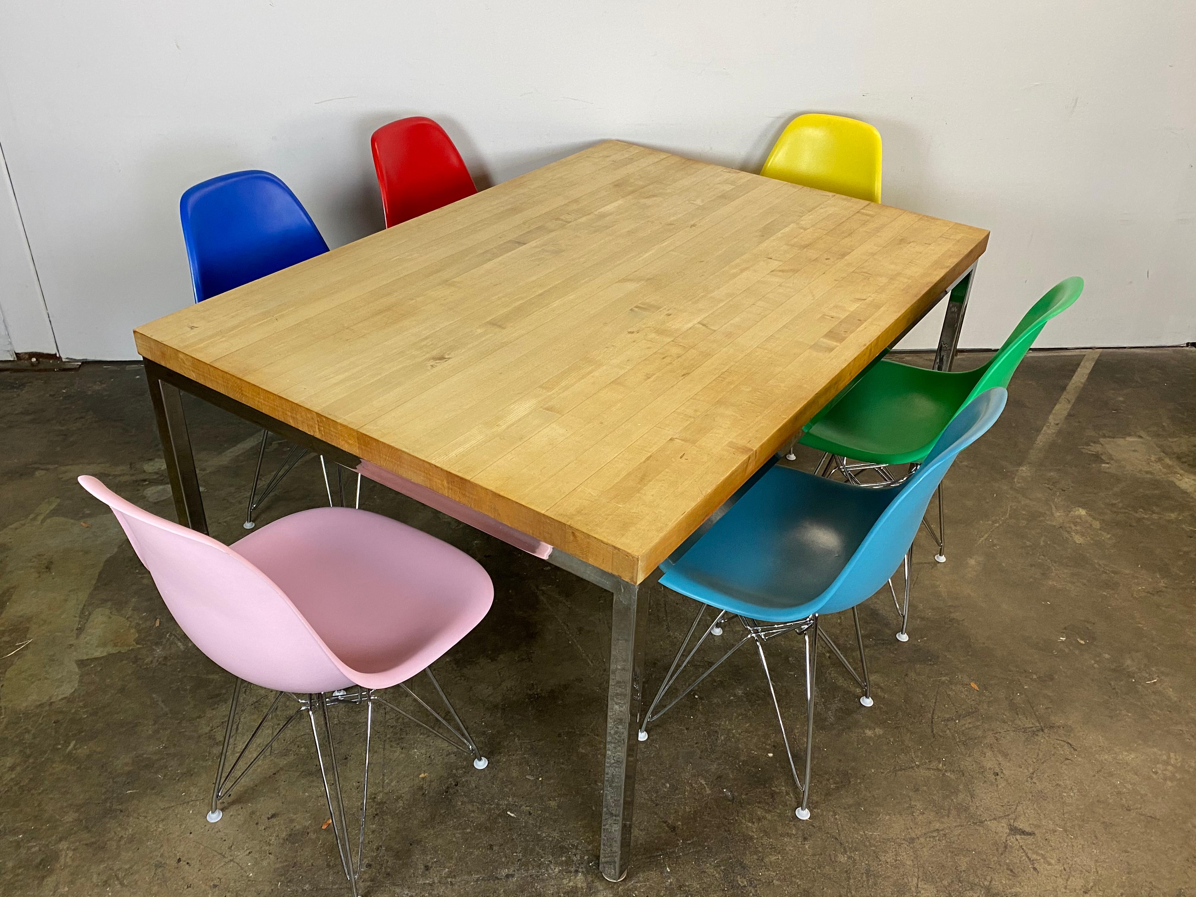 Mid-Century Modern dining set featuring maple butcher block top on steel frame. Six vintage authentic signed Herman Miller Eames fiberglass shell chairs. Originally upholstered, these have been stripped and recoated in fun colors. New chrome Eiffel