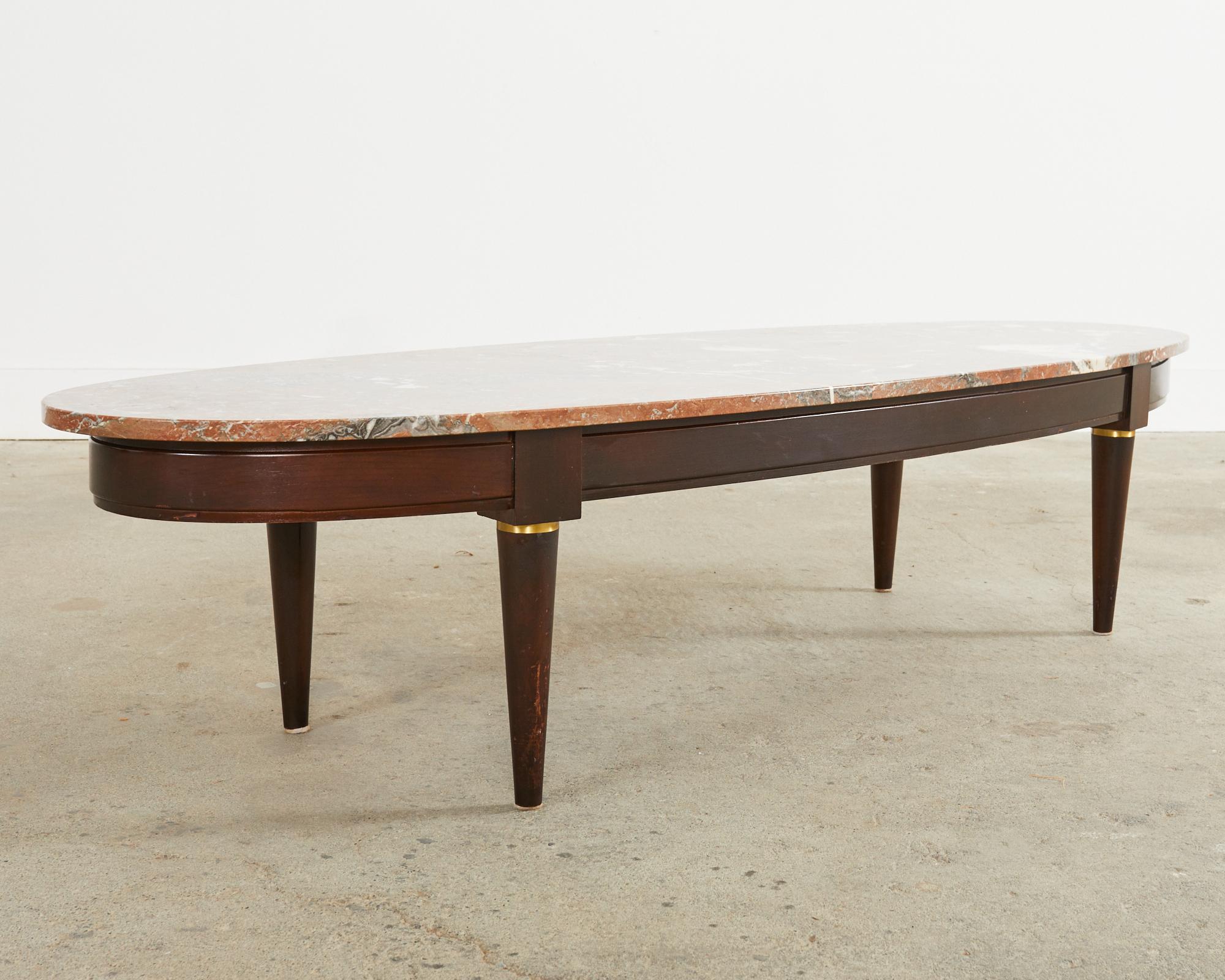 Stylish Mid-Century Modern Dutch surfboard coffee or cocktail table featuring a large, variegated marble top. The top is beautifully veined with vibrant brick red, grey, and white marbling throughout the slab. Supported by a hand-formed mahogany