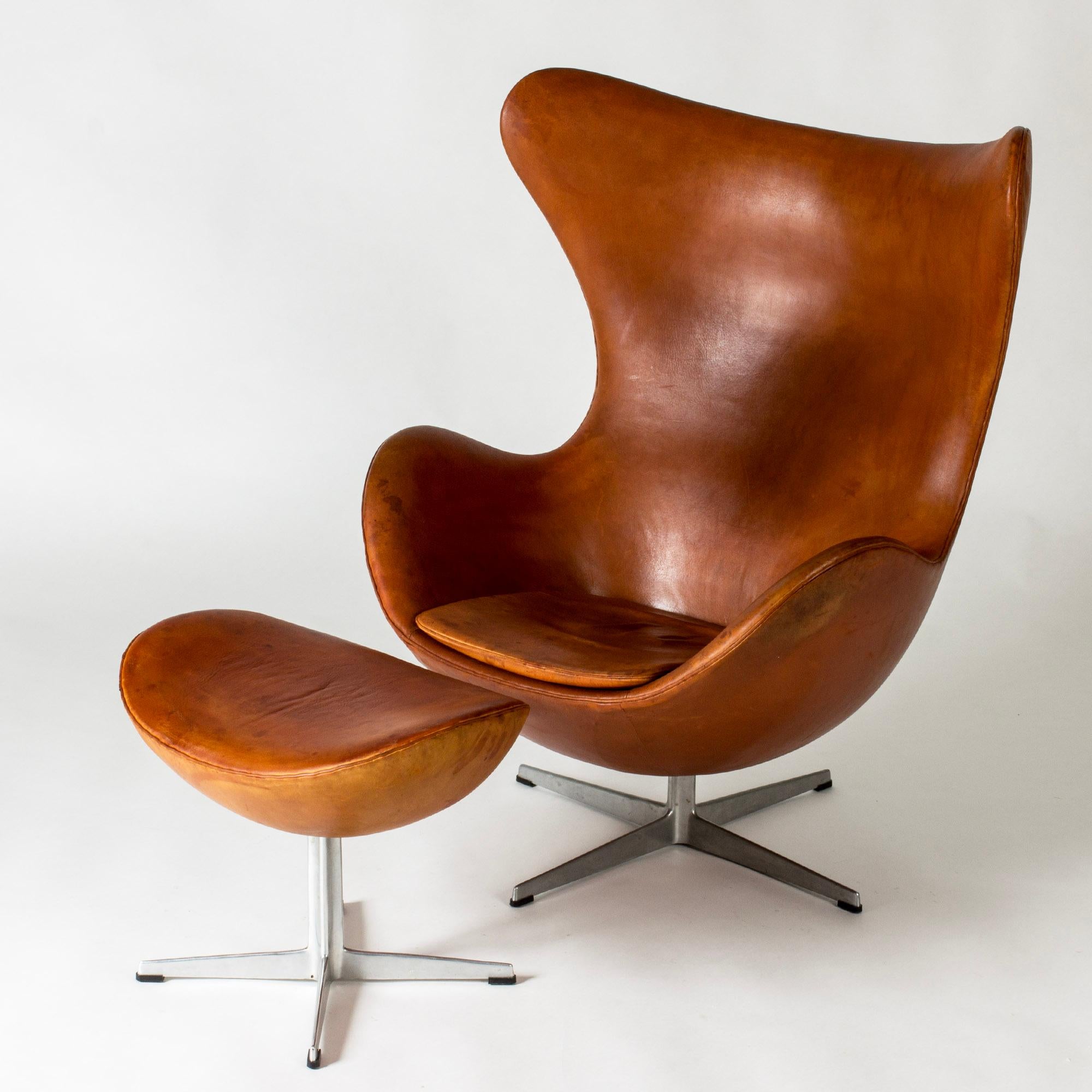 Iconic “Egg” lounge chair and footstool by Arne Jacobsen, upholstered with cognac brown leather. This design was originally made for the SAS Radisson Hotel in Copenhagen in 1958.

Ottoman dimensions:
Stool: 43 cm, width 55 cm, depth 40 cm
