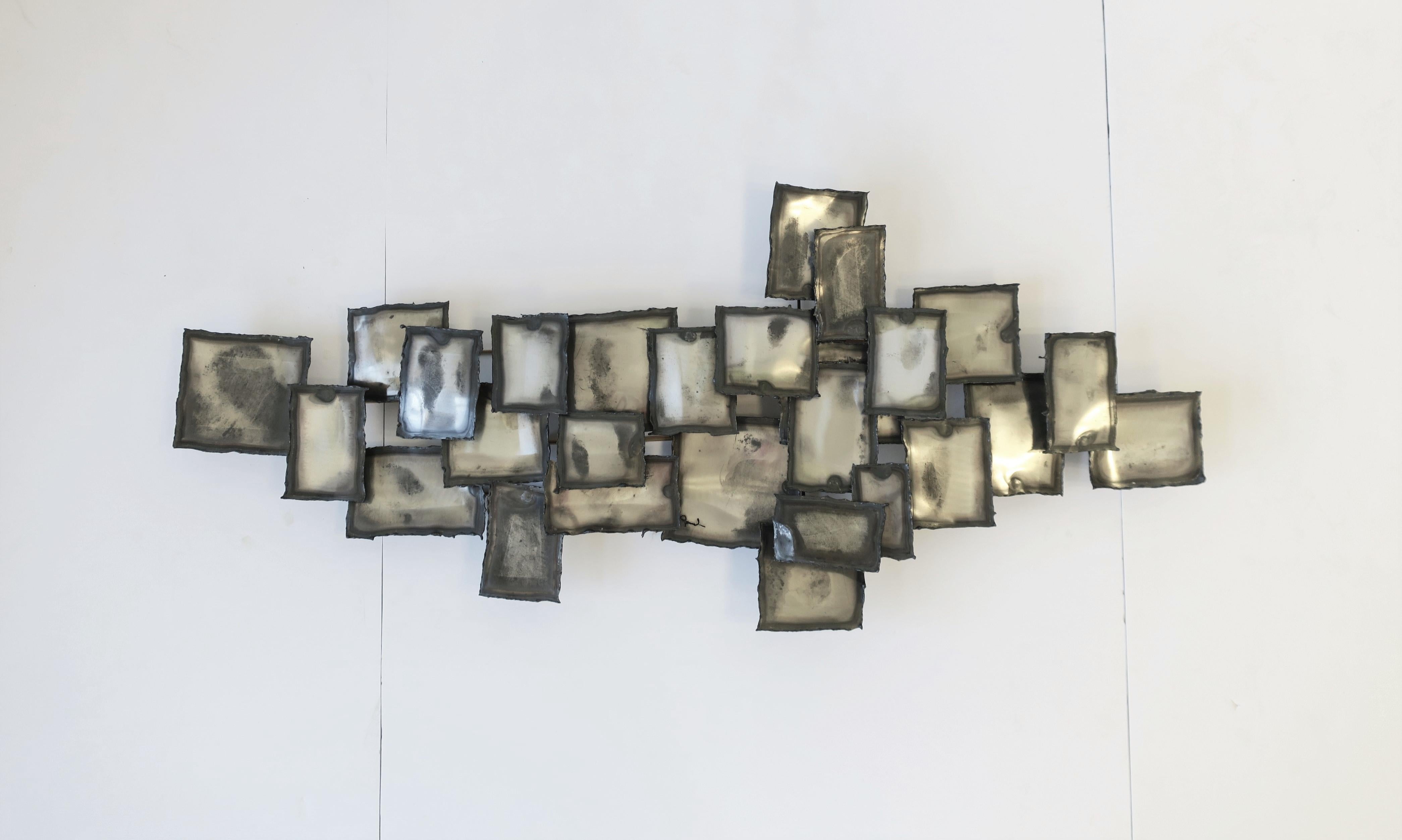A beautiful Mid-Century Modern period grey and silver metal wall art sculpture in the style of designers Curtis Jere, signed by artist, circa mid-20th century, USA. A geometric wall all sculpture piece, hand-crafted, in varying shades of grey/gray