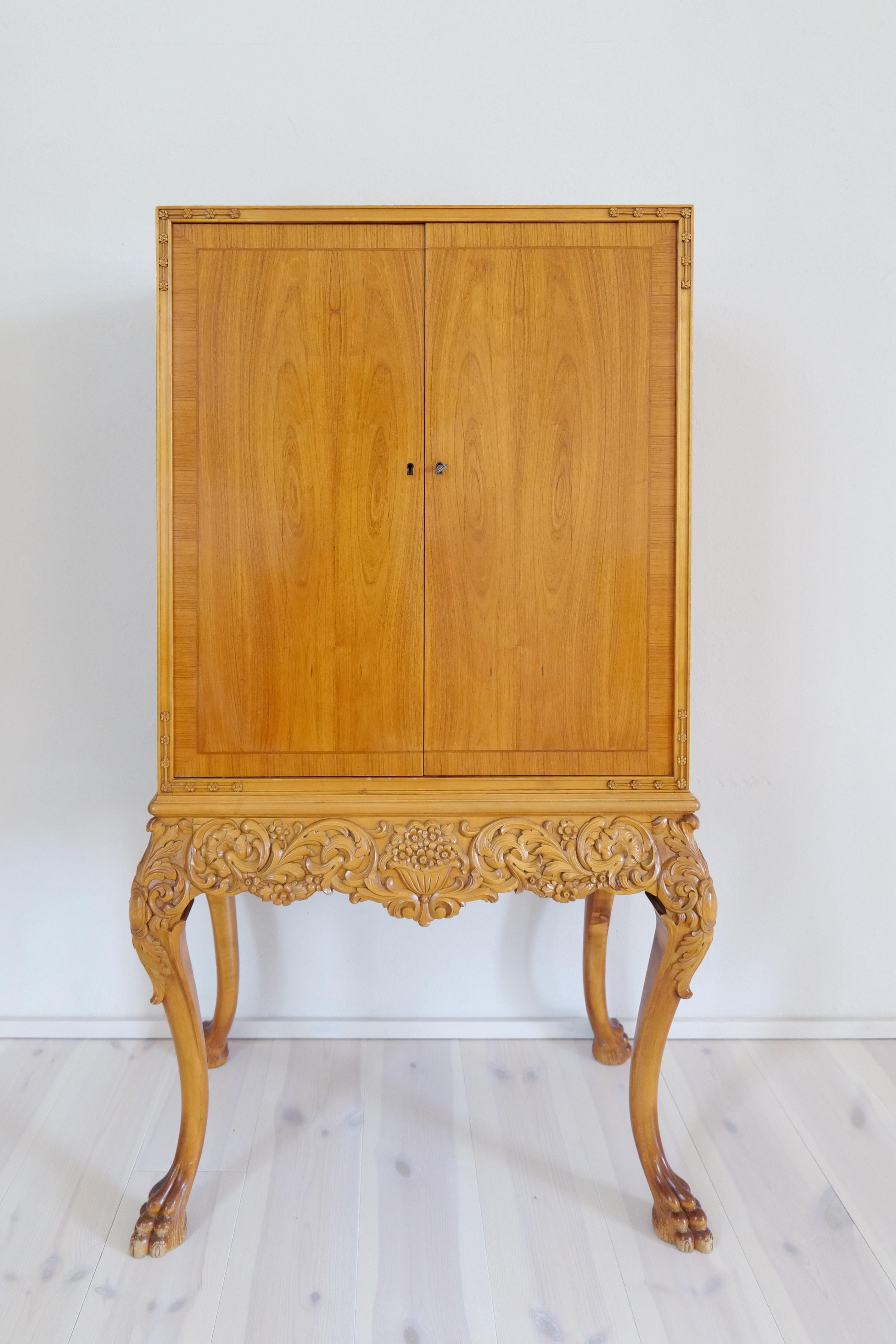 This wonderful, handcrafted cabinet is made from elm veneer. Excellent carved and curved legs as well as wonderfully veneer that gives this cabinet a luxury’s feeling.

Good vintage condition, marks and signs of use. 

Dimensions: H 150, W 79, D 44