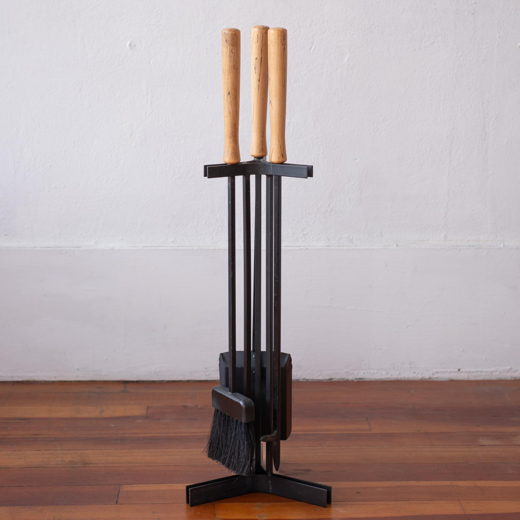 Un fantastico set di attrezzi da fuoco modernisti in ferro. Include un attizzatoio, una spazzola e una pala su un solido supporto in ferro. Maniglie in legno massiccio con una bellissima venatura. USA, anni '50
