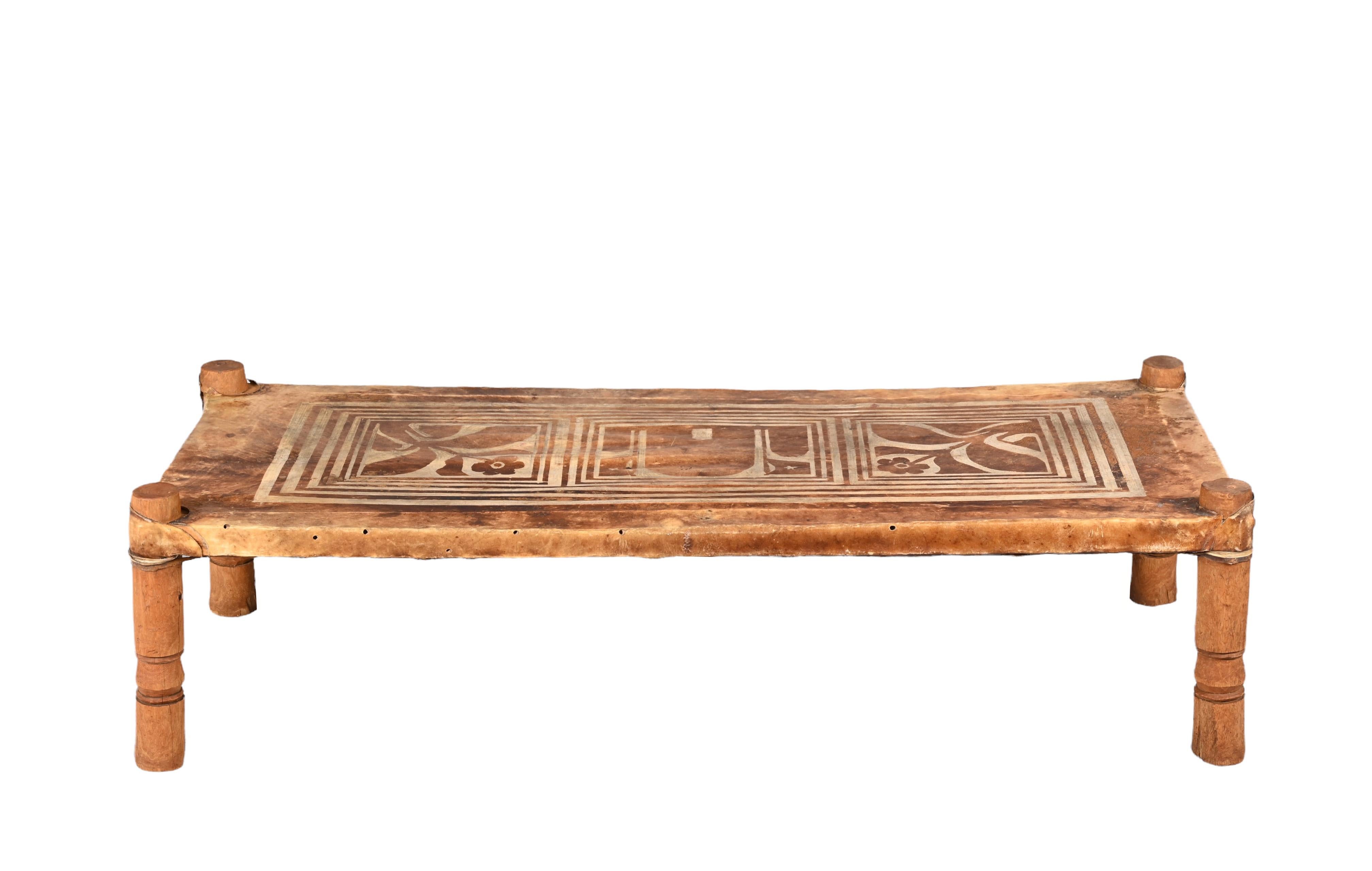 Fantastic Mid-Century Modern leather and wood rectangular coffee table or bench. This wonderful item was designed in Italy during the 1950s.

This unique piece features a light brown top in leather with fantastic tribal decorations, two flowers on
