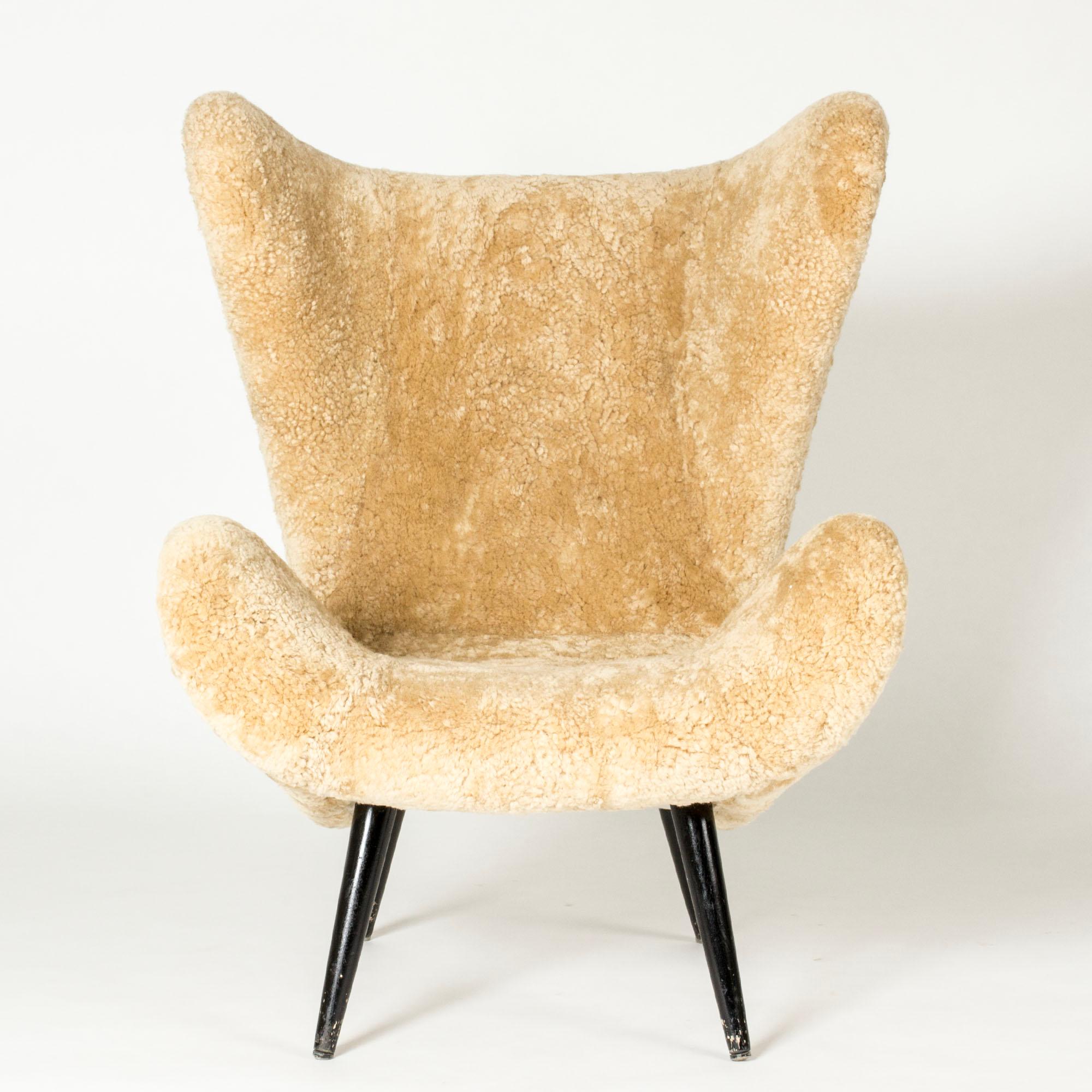 Striking Swedish Modern lounge chair with bold lines, upholstered with sheepskin. Wooden legs with original black lacquer.