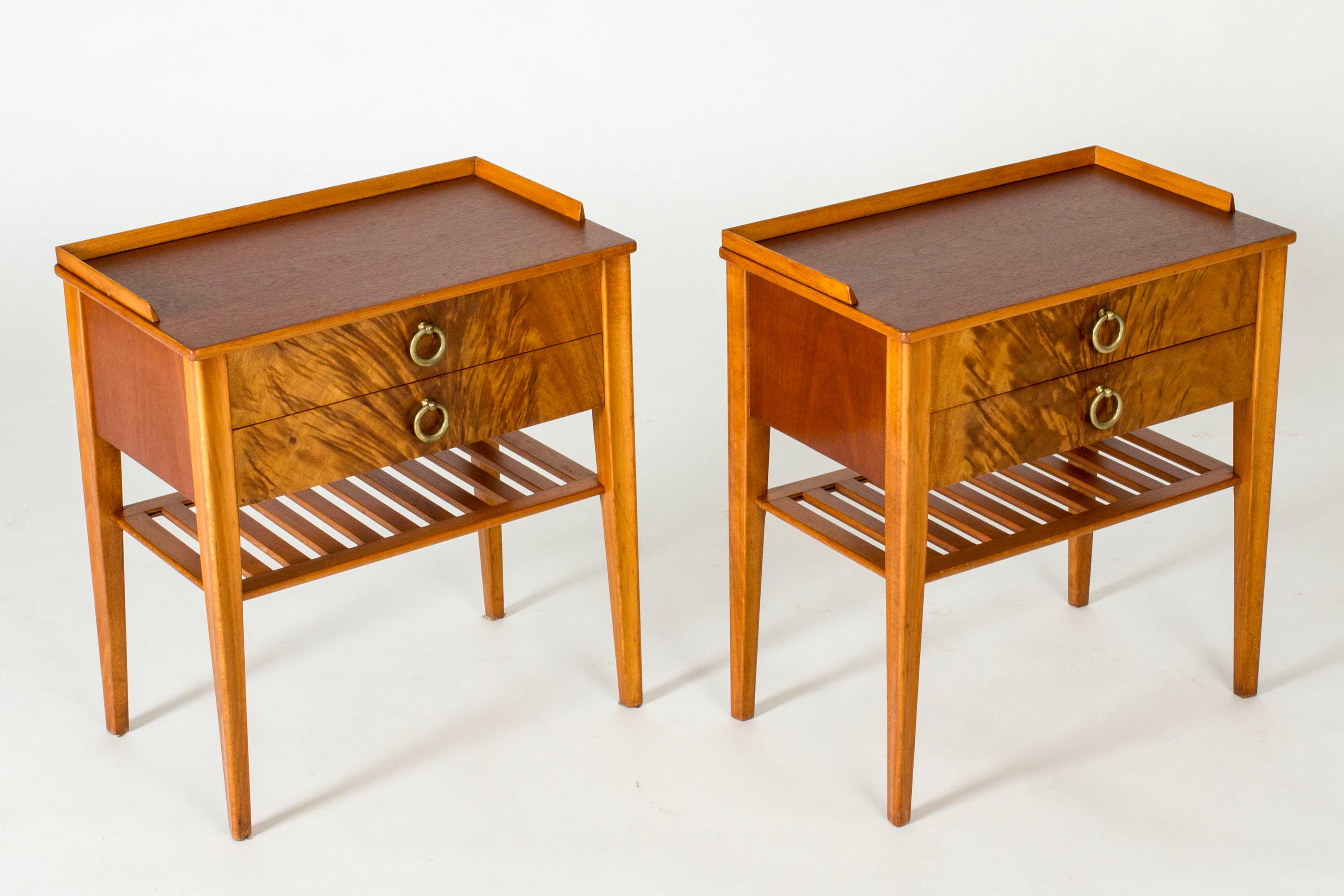 Pareja de elegantes mesillas de noche, de caoba con chapado espectacular en los frentes. Asas redondas decorativas de latón. Prácticos estantes bajo los cajones.