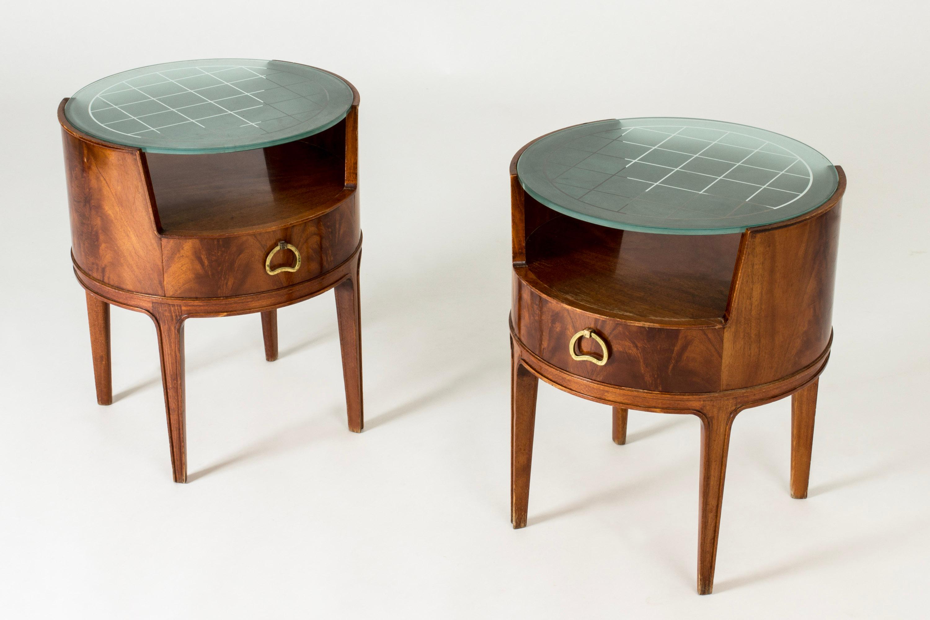 Pair of beautiful bedside tables by Axel Larsson, with pyramid mahogany veneer, frosted glass tops and sculpted brass handles. The glass tops have an etched checkered pattern.