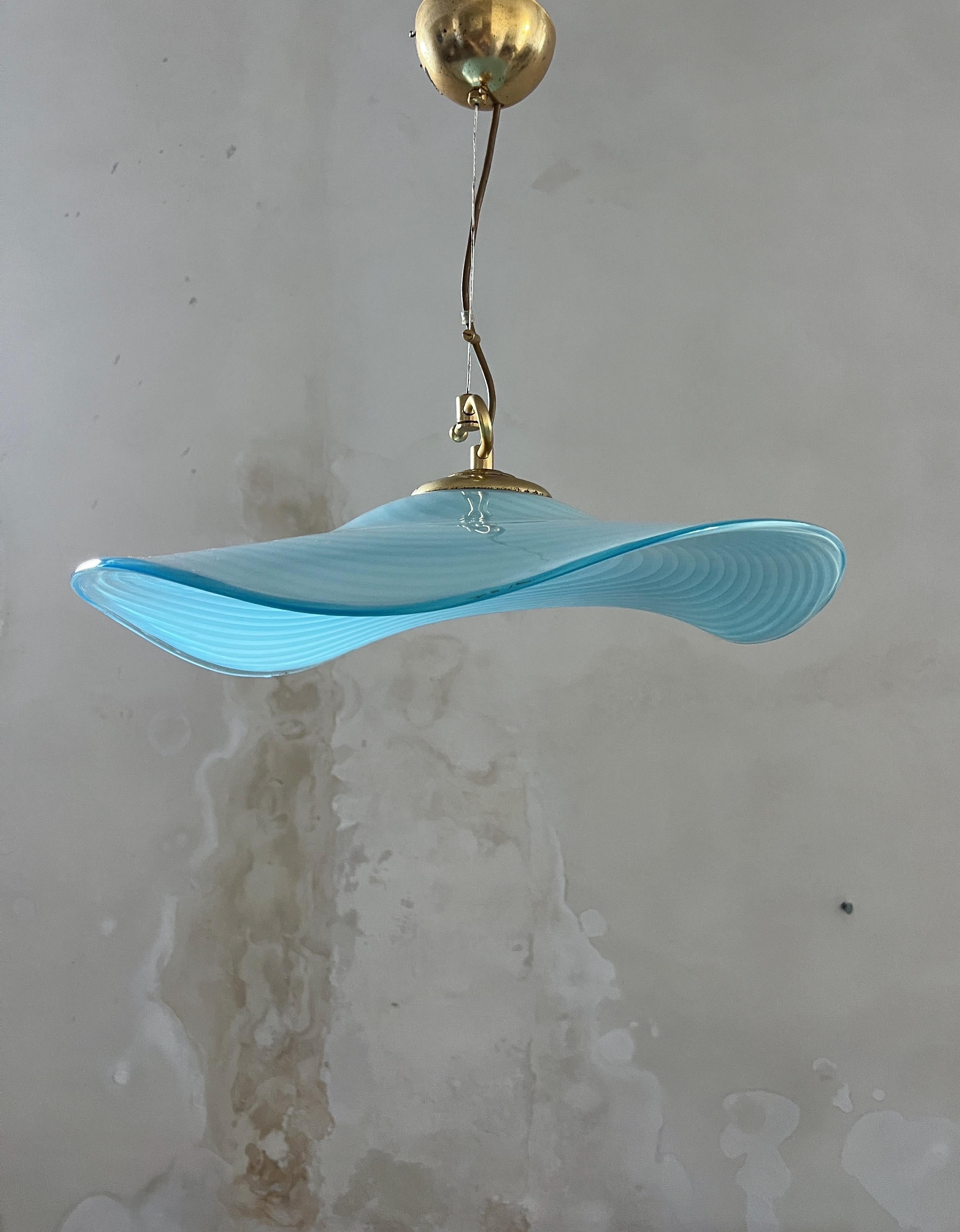 Diese außergewöhnliche Hängeleuchte aus den 1970er Jahren ist ein eindrucksvolles Beispiel für italienisches Design aus der Mitte des Jahrhunderts. Das mundgeblasene Murano-Glas ist anmutig wie ein breitkrempiger Hut geformt und verleiht dem Stück