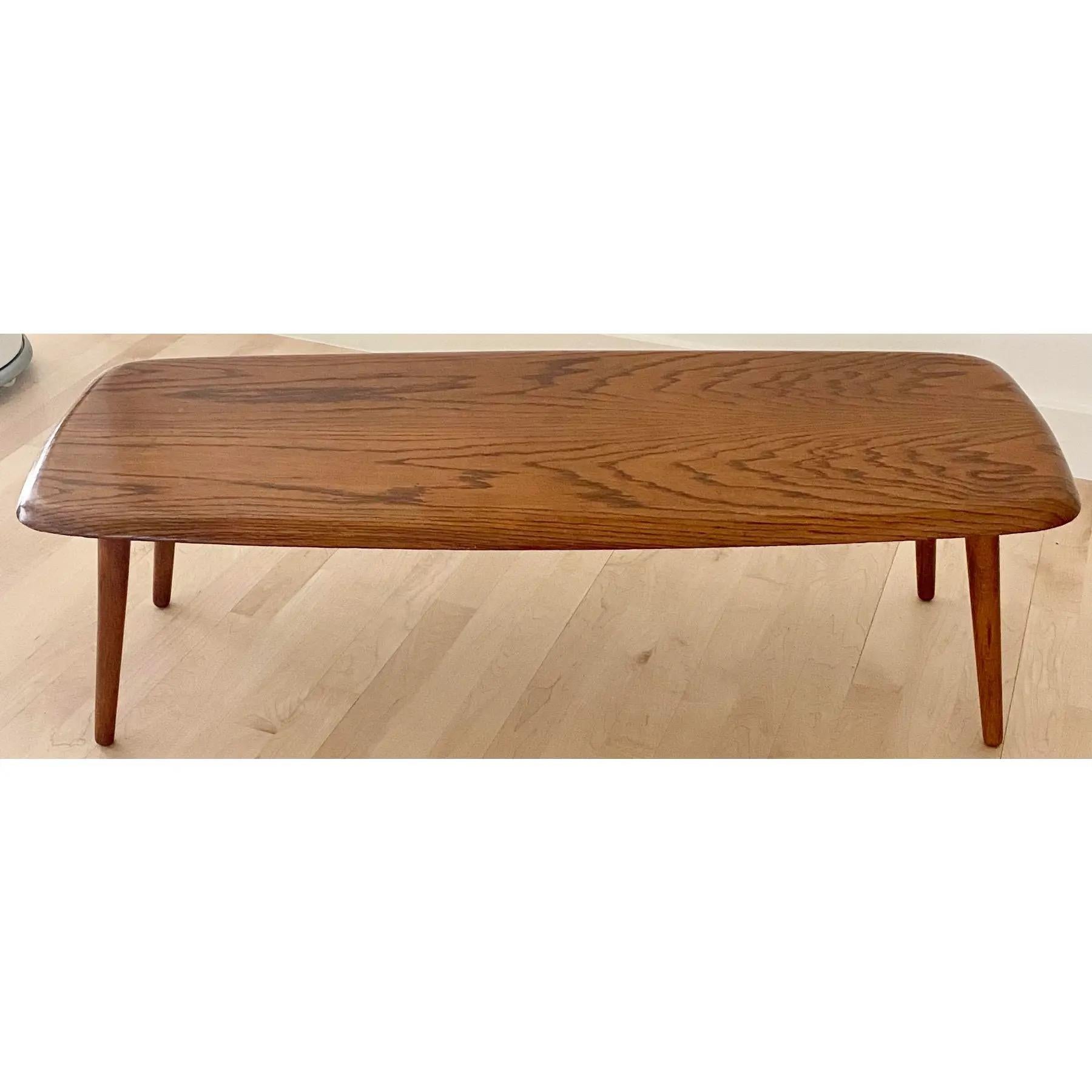 Iconic Midcentury Modern coffee table on tapered legs in oak. Gorgeous undulating grain, sturdy and nicely crafted. Simple enough to mix into any living room or space where a low table can support an array of plants, a few magazines, and a piece of