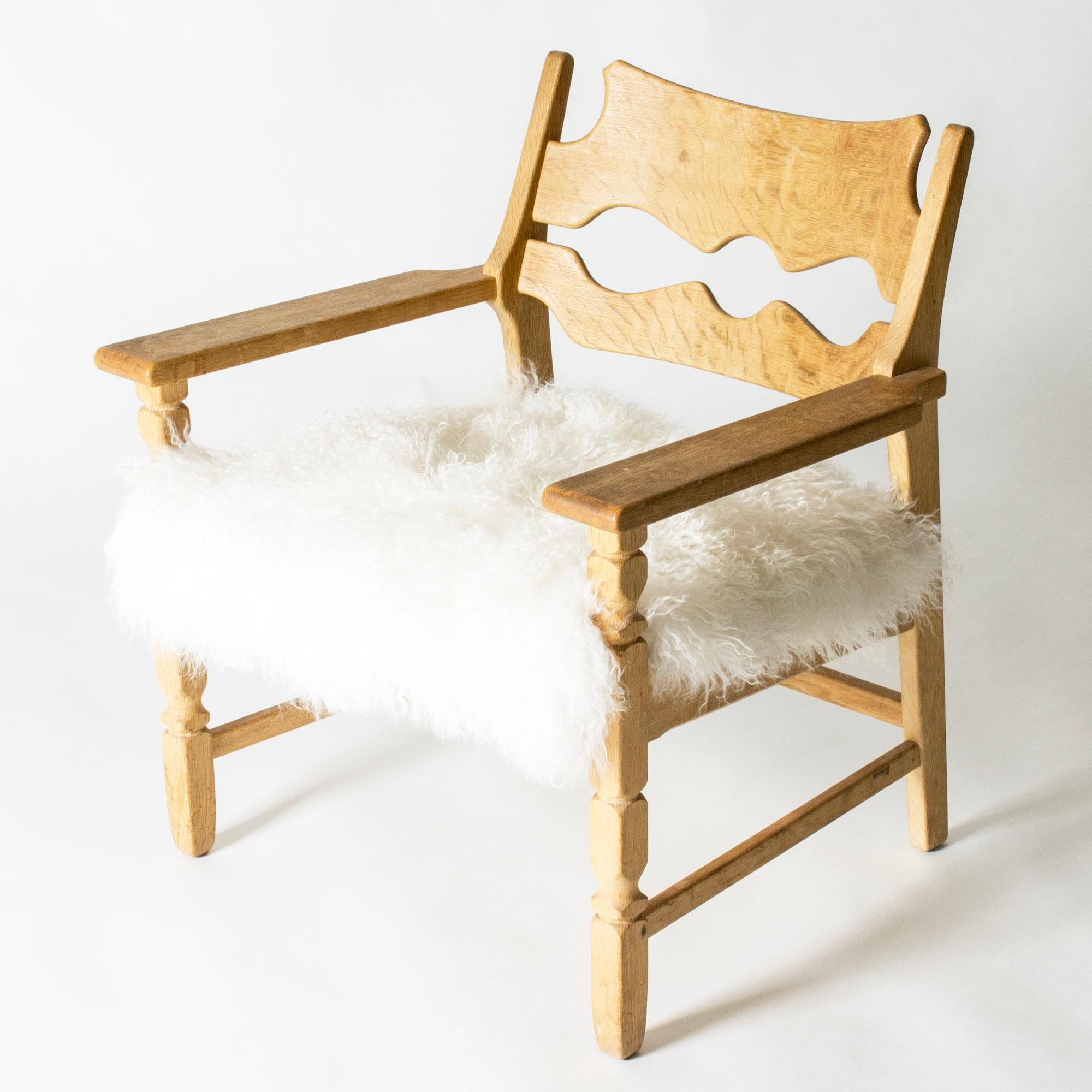 Cool “Razorblade” lounge chair by Henning Kjaernulf, in a rustic meets modernism design. Made of oak with beautiful wood grain, upholstered with Tibetan sheepskin.