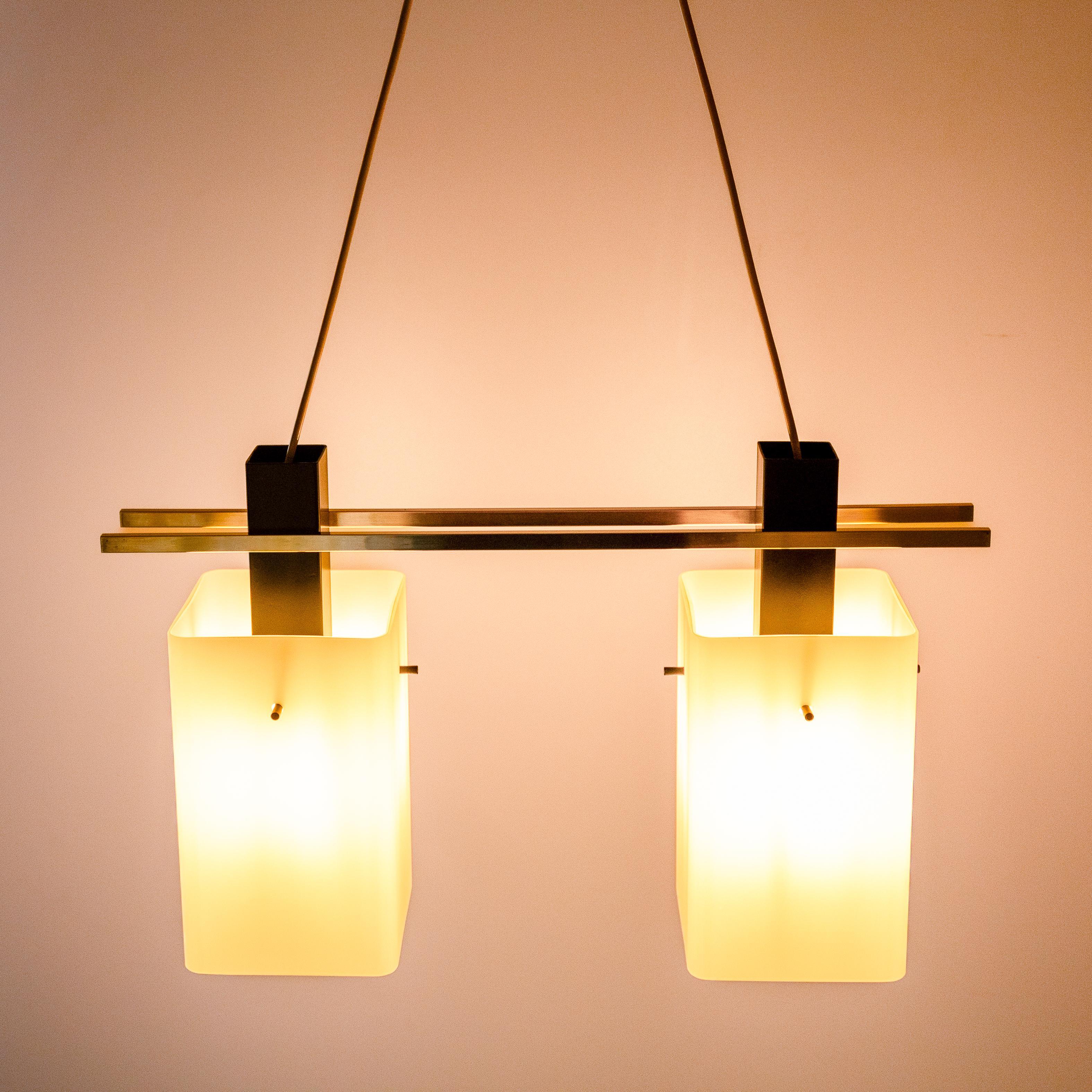Ciondolo da soffitto Stilnovo anni '60 con paralumi in vetro opalino e dettagli in ottone

Una suggestiva e autentica lampada a sospensione di metà secolo di Stilnovo, realizzata in Italia negli anni '50-'60. Questo raffinato apparecchio presenta