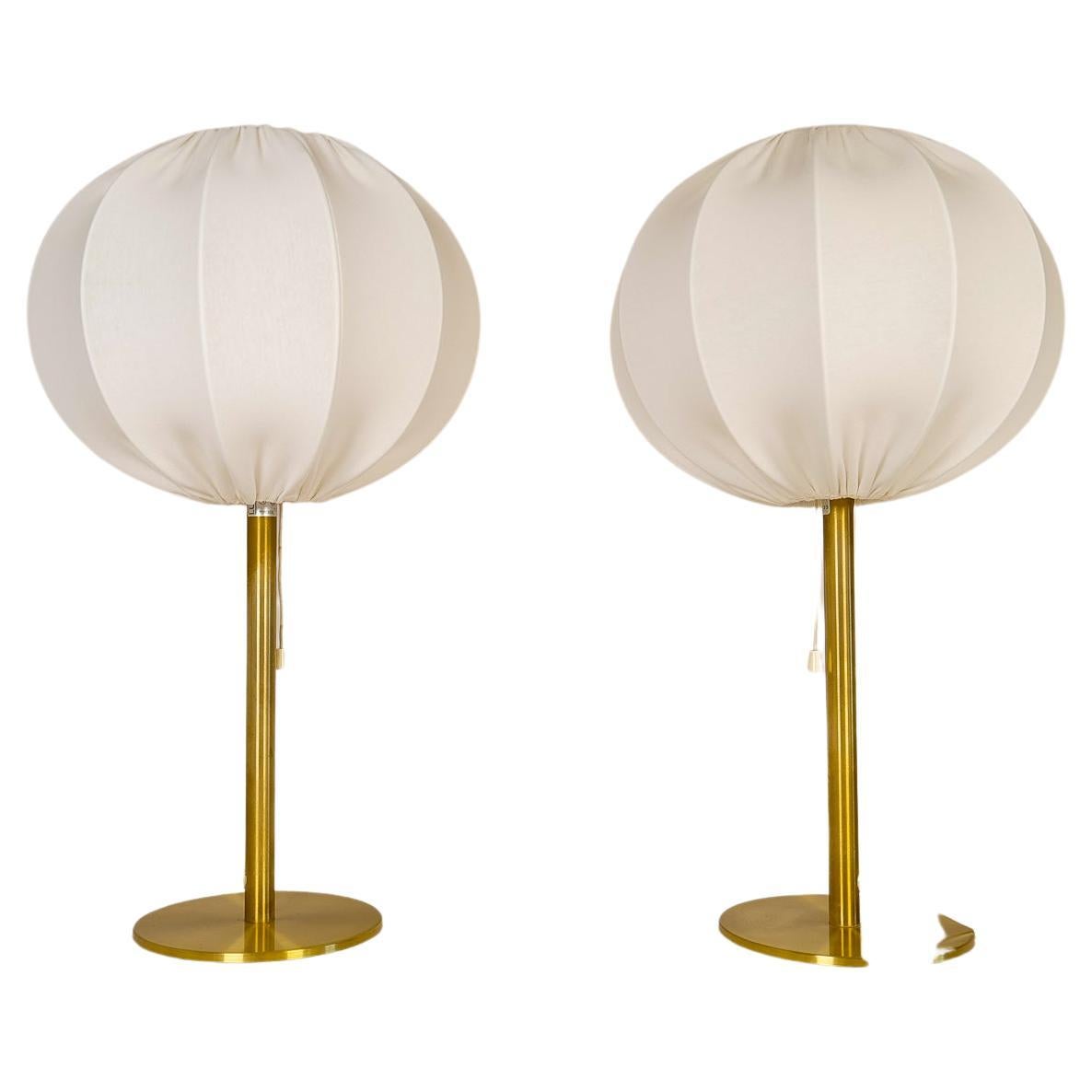These Mid-Century Modern table lamps were manufactured in Sweden for Luxus. The rounded base and rod are made in brass. These lamps come with both the new cotton cloud rounded shades made in Sweden as well as the original upplight shades in acrylic.
