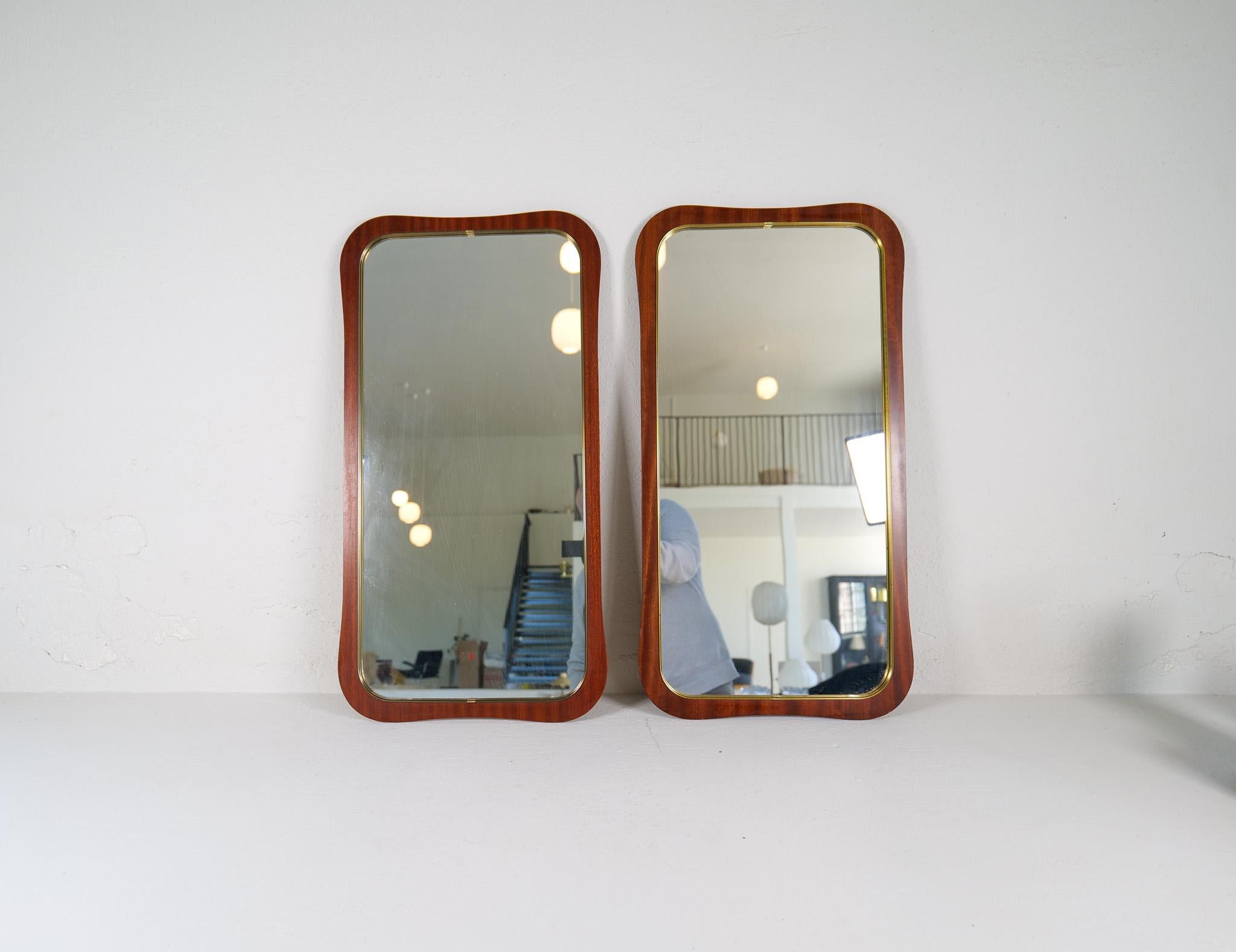 Dieses Paar skulpturaler Spiegel wurde in den späten 1950er Jahren in Schweden hergestellt. Geschenkt mit dem eleganten Swedish Grace Design, hergestellt aus Mahagonifurnier mit Messingrahmen. 

Guter Vintage-Zustand, kleine Flecken auf dem Holz und