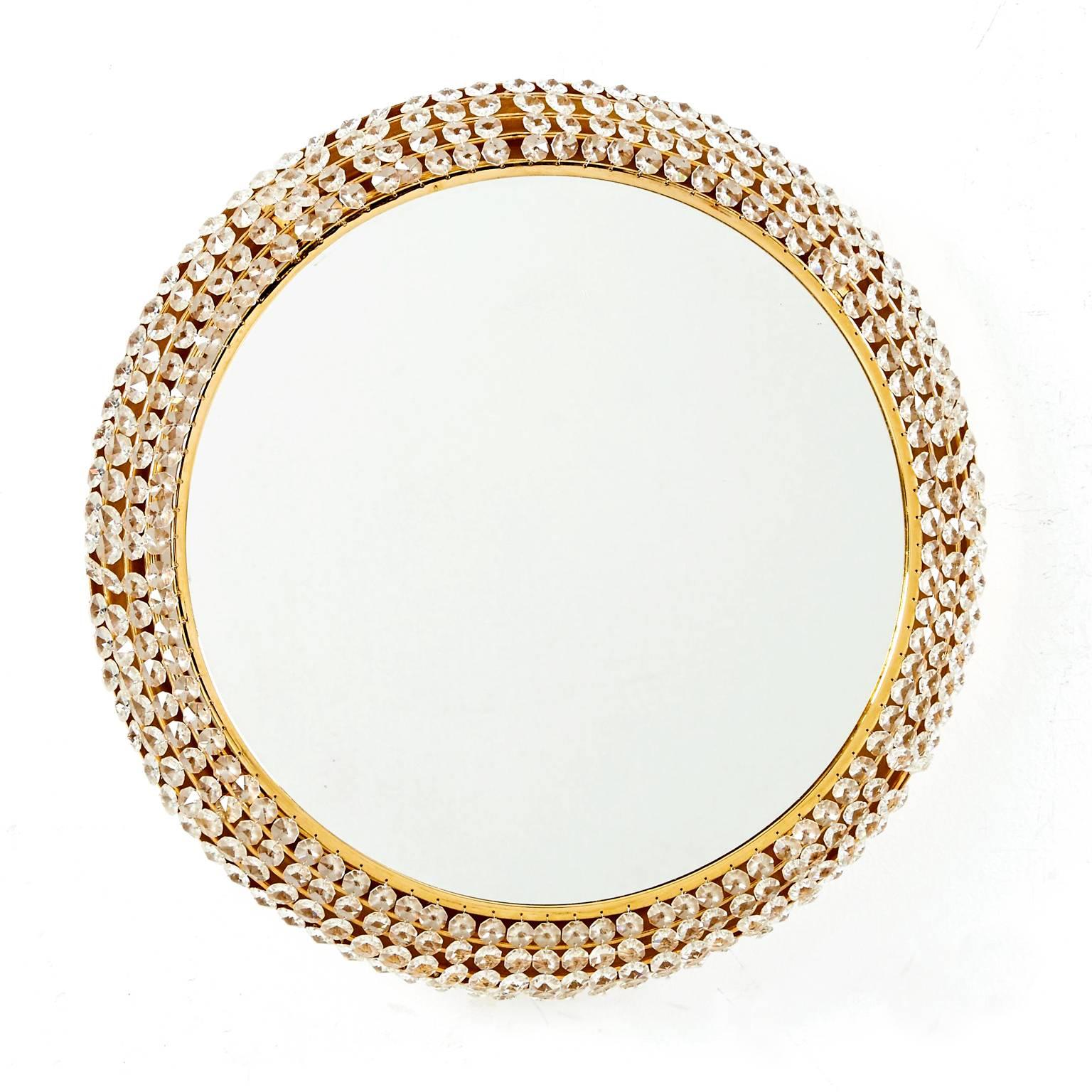 A brilliant Midcentury Modern gilded brass round mirror with dozens of rows of crystals suspended over an electrified backplate holding six candelabra base sockets. Newly rewired, the mirror has an external lead with plug but may easily be mounted