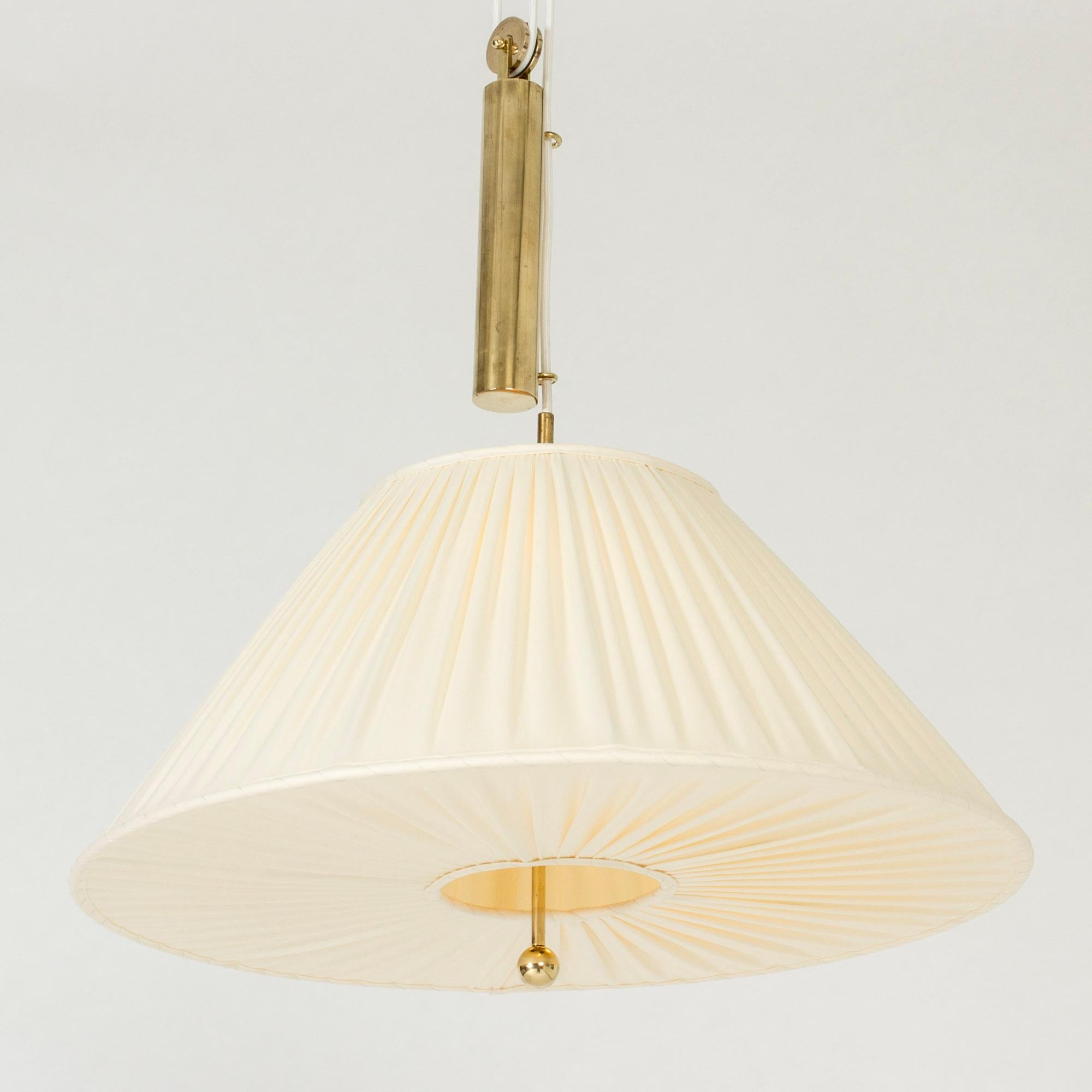 Beautiful brass pendant light by Josef Frank, in an elegant, voluminous design. Shade made from pleated fabric. Decorative brass ball coming out at the bottom, brass weight for adjusting the height.

Height 120-220 cm (adjustable).
