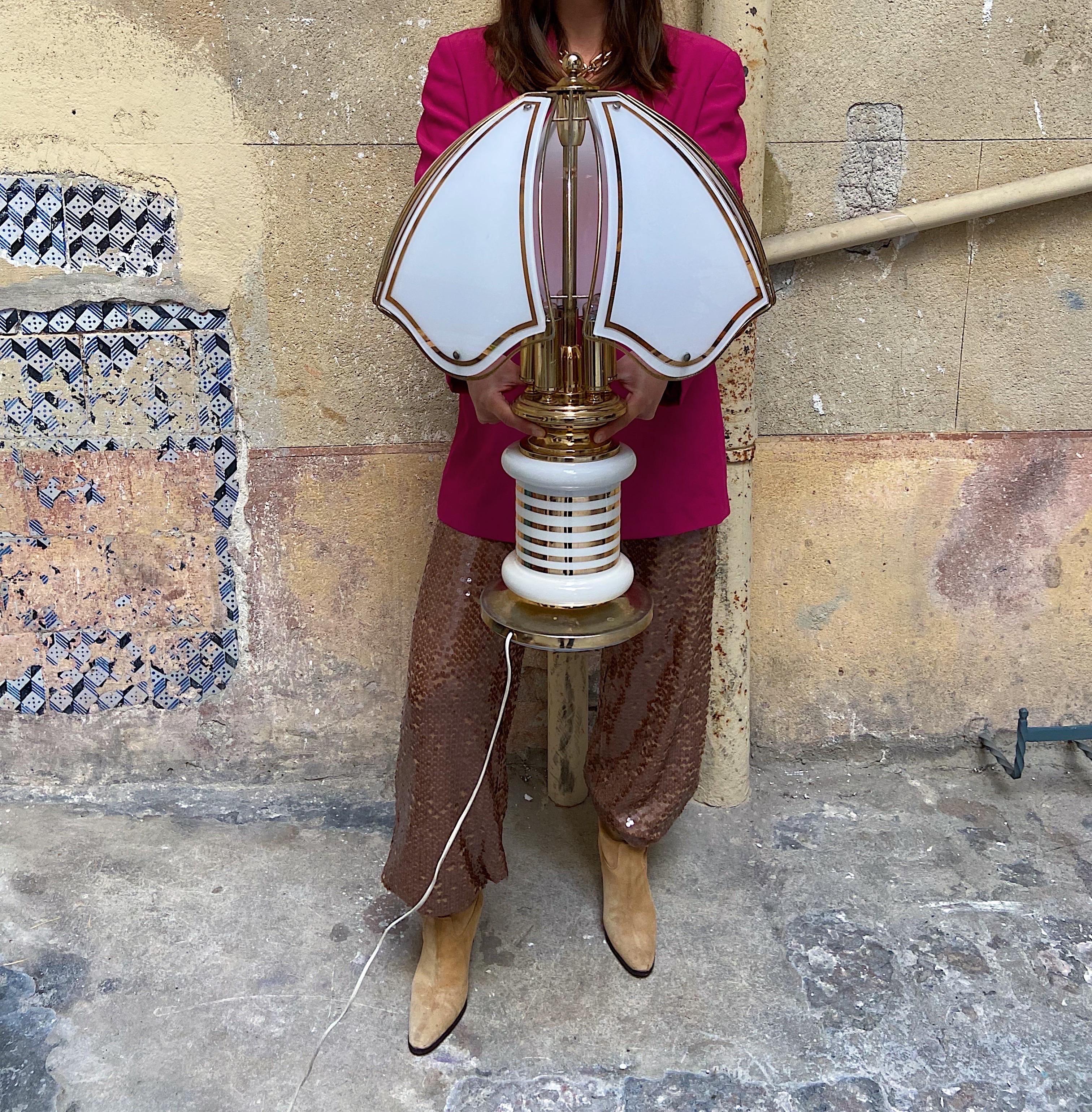 Eccentric table lamp that screams the best of Italian 80s.
Gold plated metal and white porcelain base with gold decor.
The shade is in metal with 5 glass petals.
Any type of light bulb with an E14 screw base can be used.
5 light