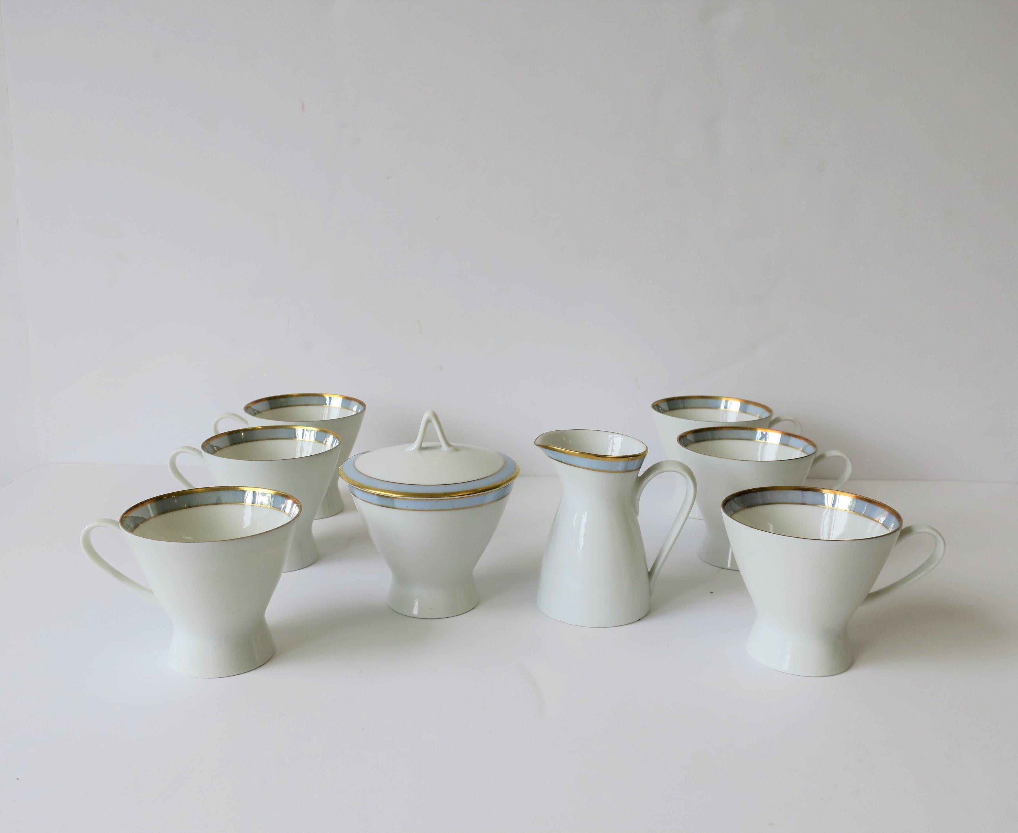 A beautiful German porcelain coffee or tea cup set, with creamer and sugar, in white with touches of gold and blue. Set includes six cups, one creamer and one sugar bowl with lid, all by Rosenthal, Germany, circa mid-20th century. Marker's mark on