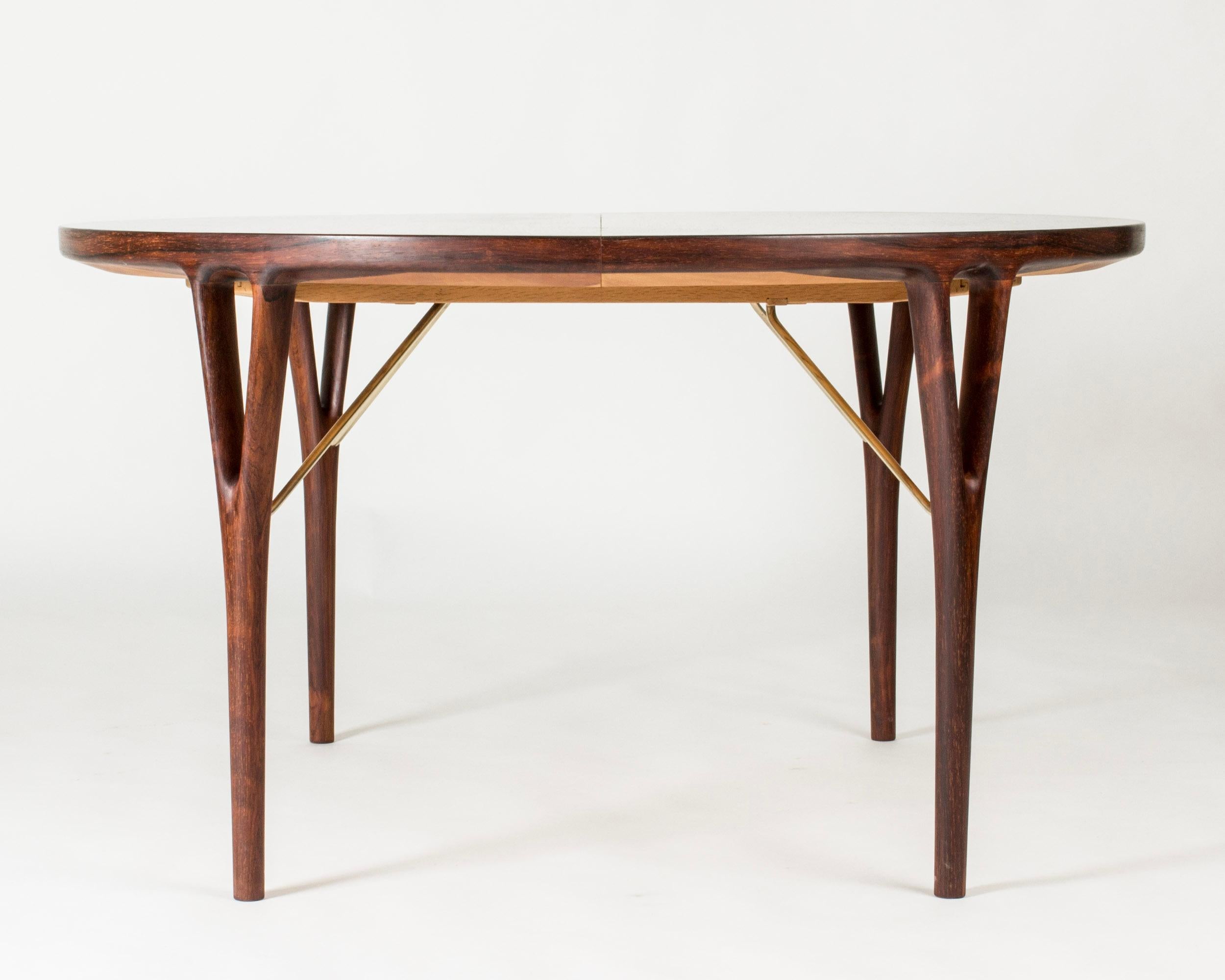 Stunning rosewood dining table by Helge Vestergaard Jensen with beautifully sculpted legs and decorative brass stabilizers. Three extension leaves which makes the table very versatile and able to seat a big dinner party in style.

Height 72 d 130 cm