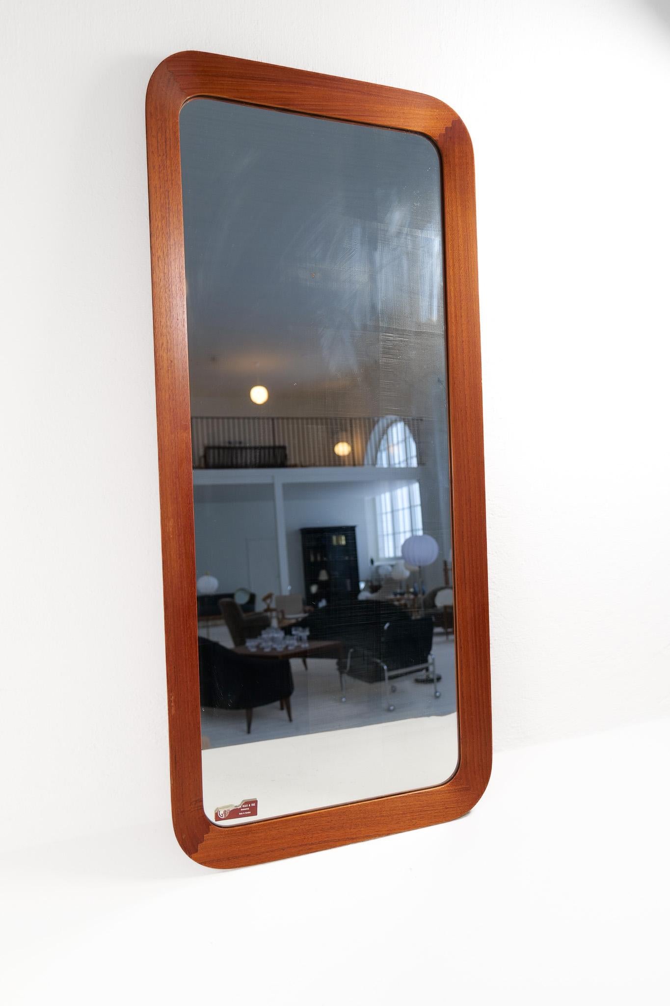 Wonderful organic wall mirror produced by AB Glas & Trä, Hovmantorp, Sweden. In sculpted Teak and crystal mirror glass, labeled. 

Good vintage condition, with some scratches on the wood, distressed/dizzy glass.

Dimensions: Height: 41.3 in. (105cm)