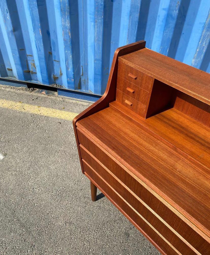 Lovely Midcentury modern secretary in teakwood, 1960s Denmark.
This exquisite piece features a vibrant wood grain, a set of three small drawers, mail slots and slide out writing desk with a hidden mirror on its top while the lower end offers three