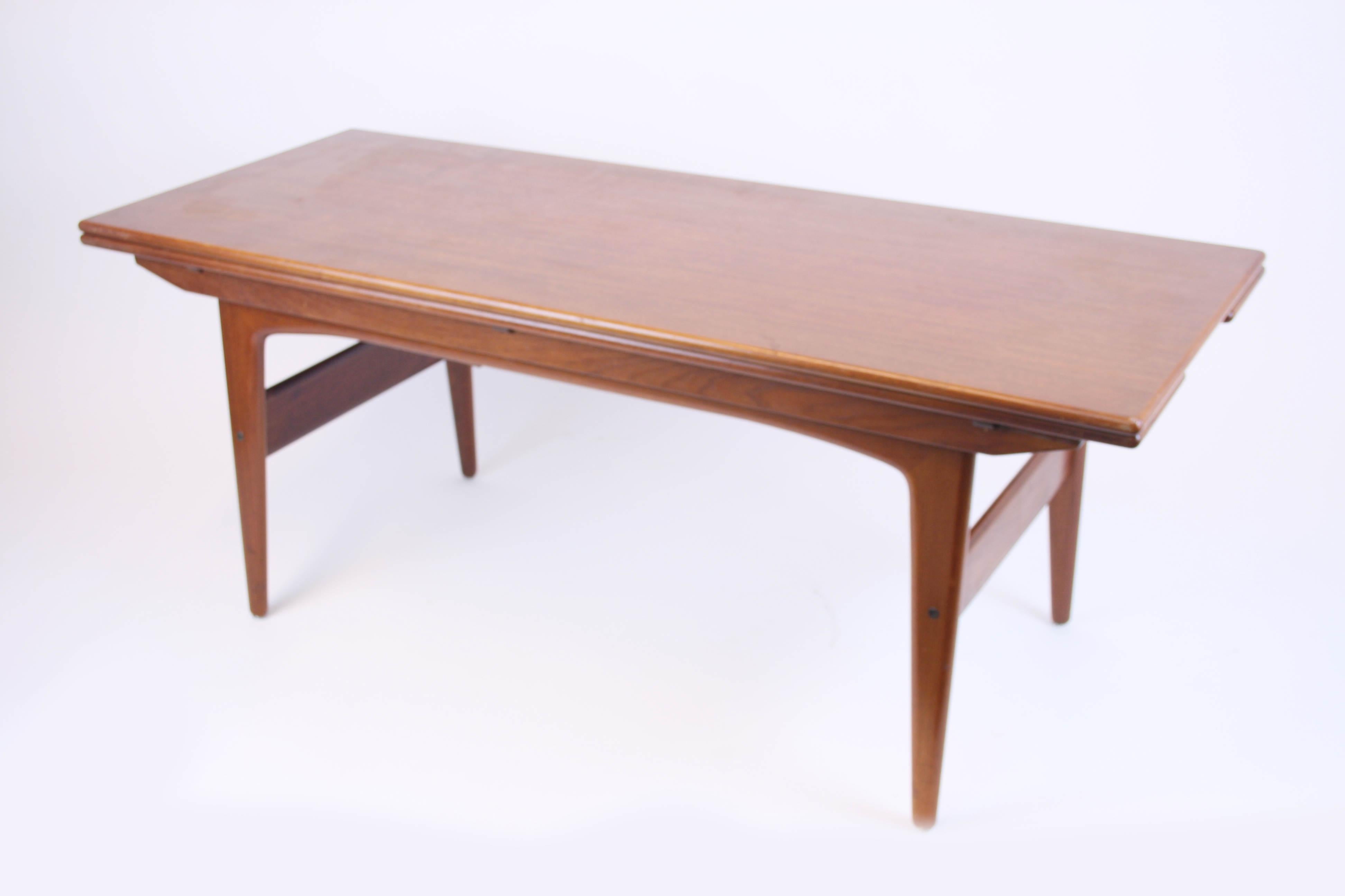 Mid-Century Modern side table or sofa table by Trioh Denmark, manufactured of solid teak wood. This object offers two applications it can easily be transformed into a dining table by lifting and expanding the integrated sidepanels. As a dining table