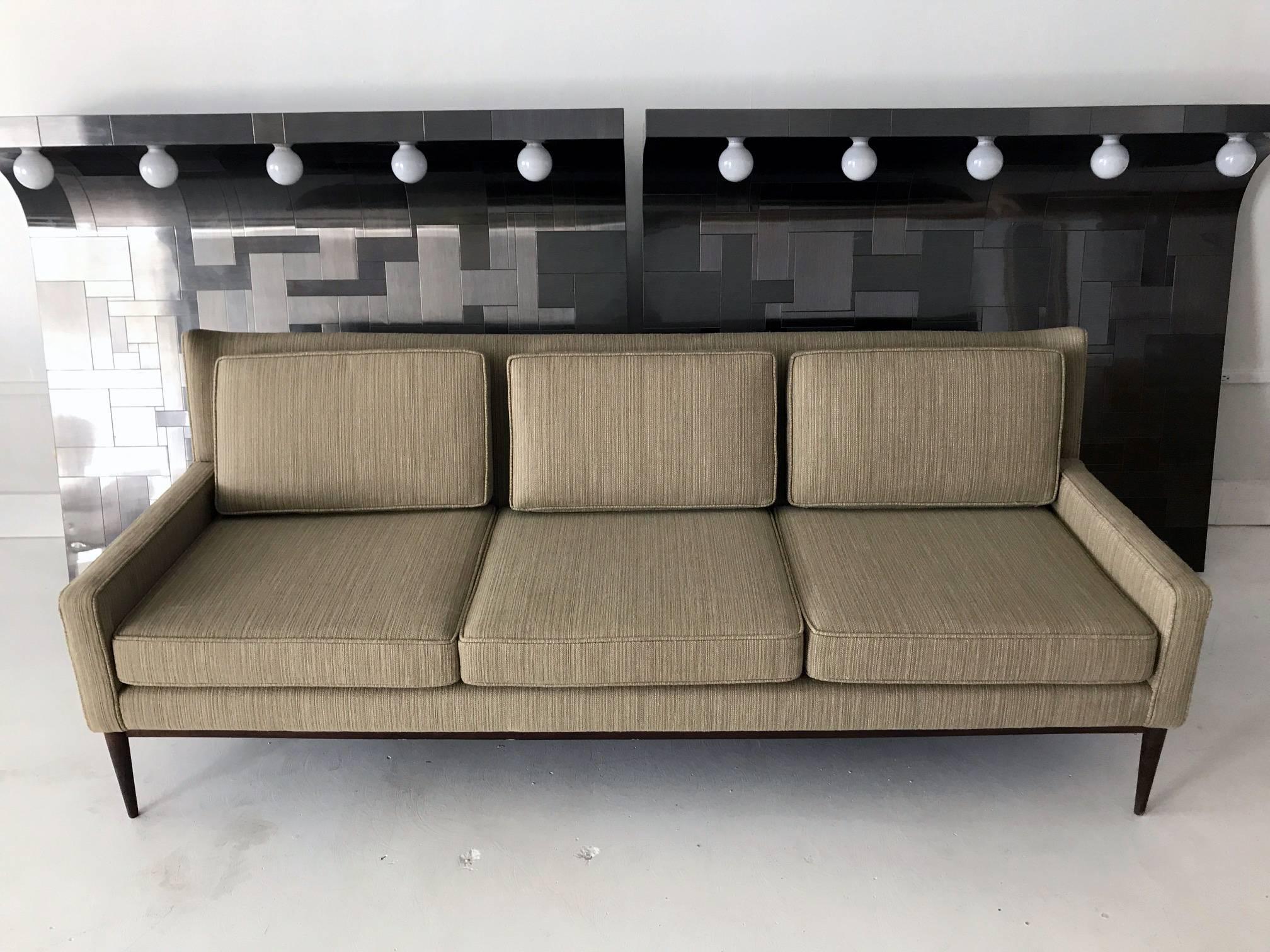 A midcentury three-seat sofa by Paul McCobb for Directional, model 1301, circa 1950s-1960s. A very clean look with a design nodding to the wing back chair. It features three removable back and seat cushions on a conforming upholstered frame,