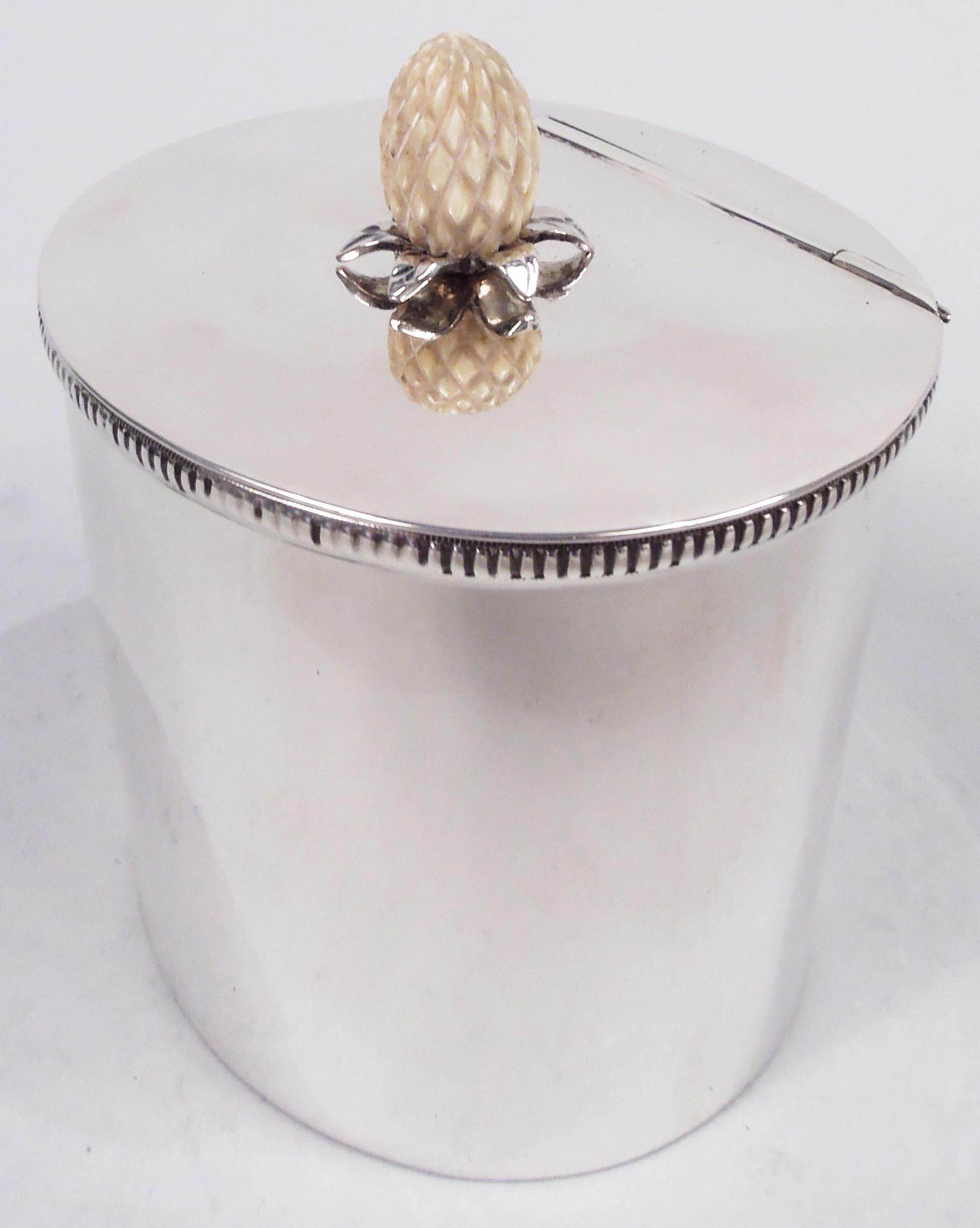 Midcentury Modern sterling silver tea caddy. Oval with straight sides and gadrooned and ribbed mouth rim. Cover flat and hinged with carved pineapple finial on tooled silver leaf mounts. Spare elegance that suggests the Danish influence. Marked