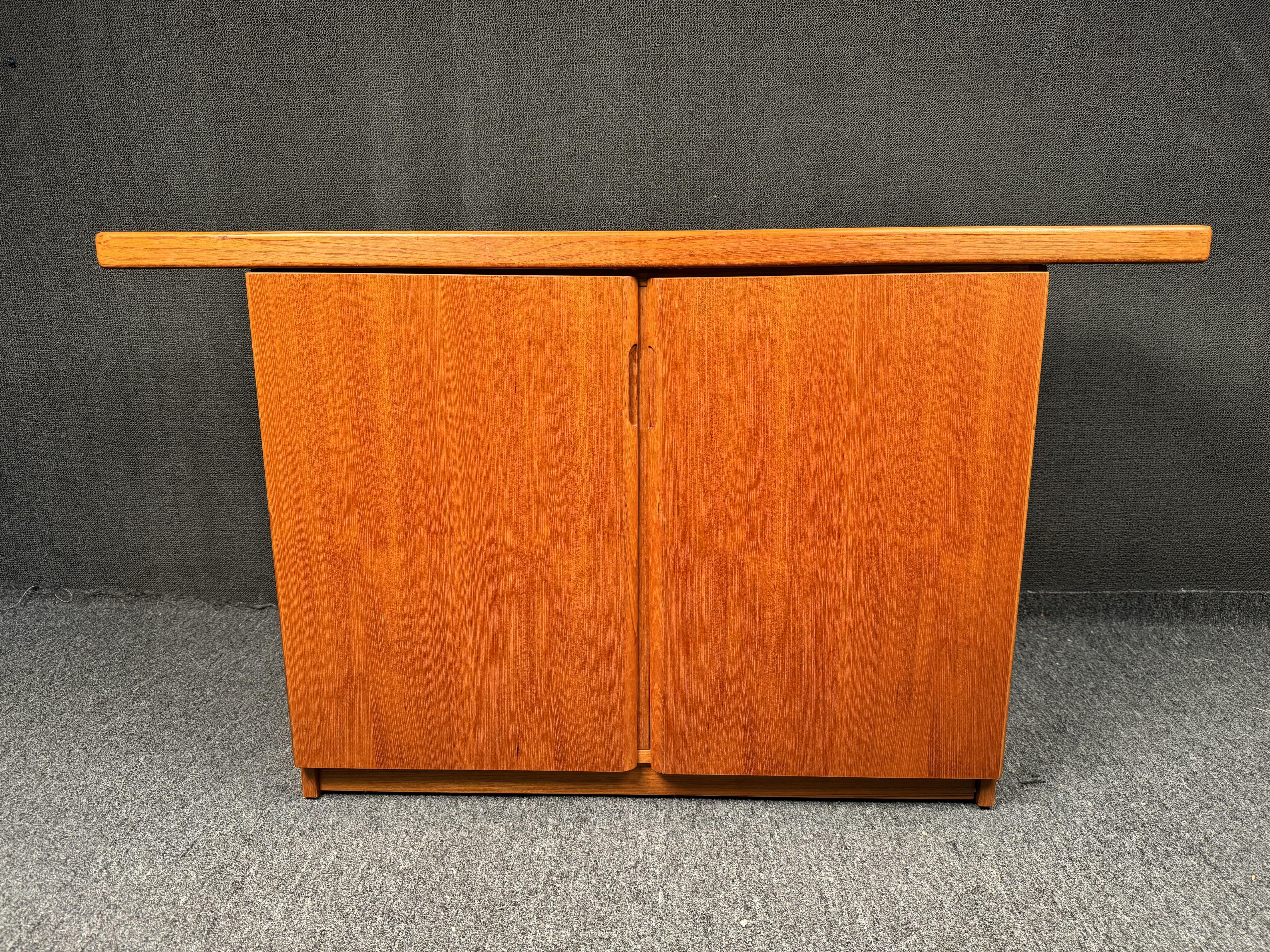A Midcentury Modern design console, server, sideboard or bar cabinet in golden genuine teak. Inside are adjustable shelves for ample storage. Perfect addition to any living space in need of storage. Please confirm location with seller (NY or NJ)