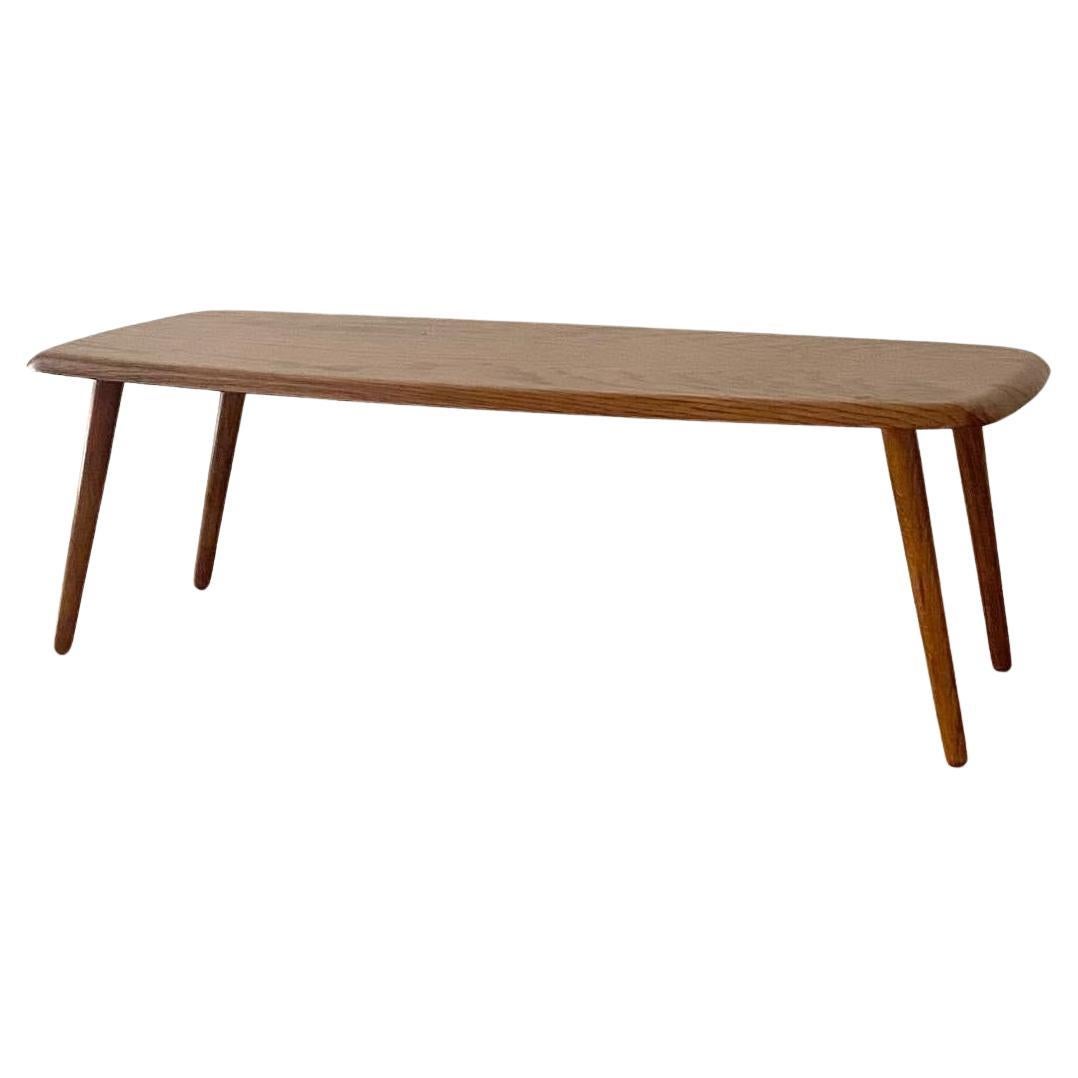 Iconic Midcentury Modern coffee table on tapered legs in oak. Gorgeous undulating grain, sturdy and nicely crafted. Simple enough to mix into any living room or space where a low table can support an array of plants, a few magazines, and a piece of