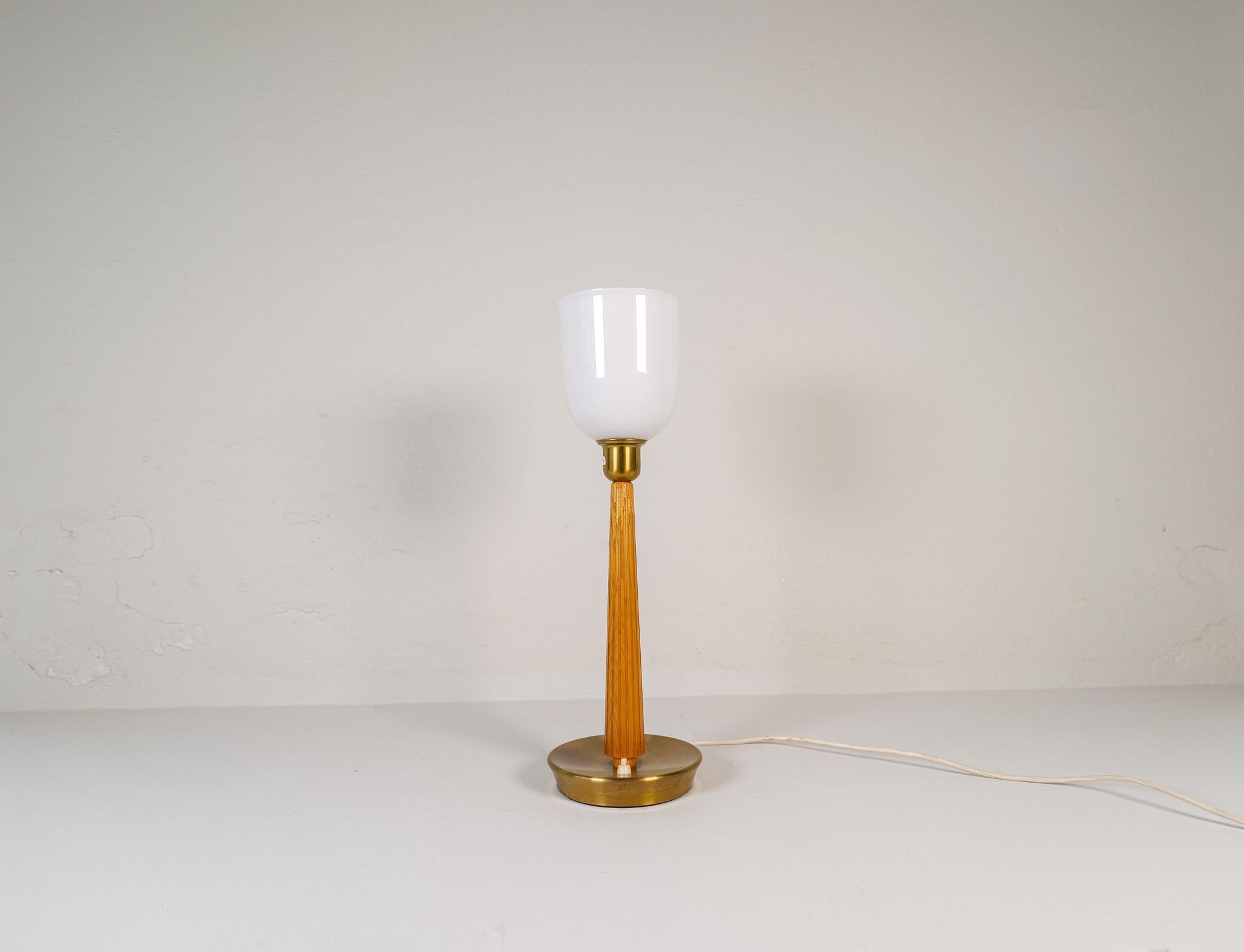 Genuinely nice Swedish table lamp made in the 1940s for ASEA and designed by Hans Bergström. With a brass base and a wooden rod leading up to a opaline glass. 

Good condition with some wear consistent with age and use. The brass base can be