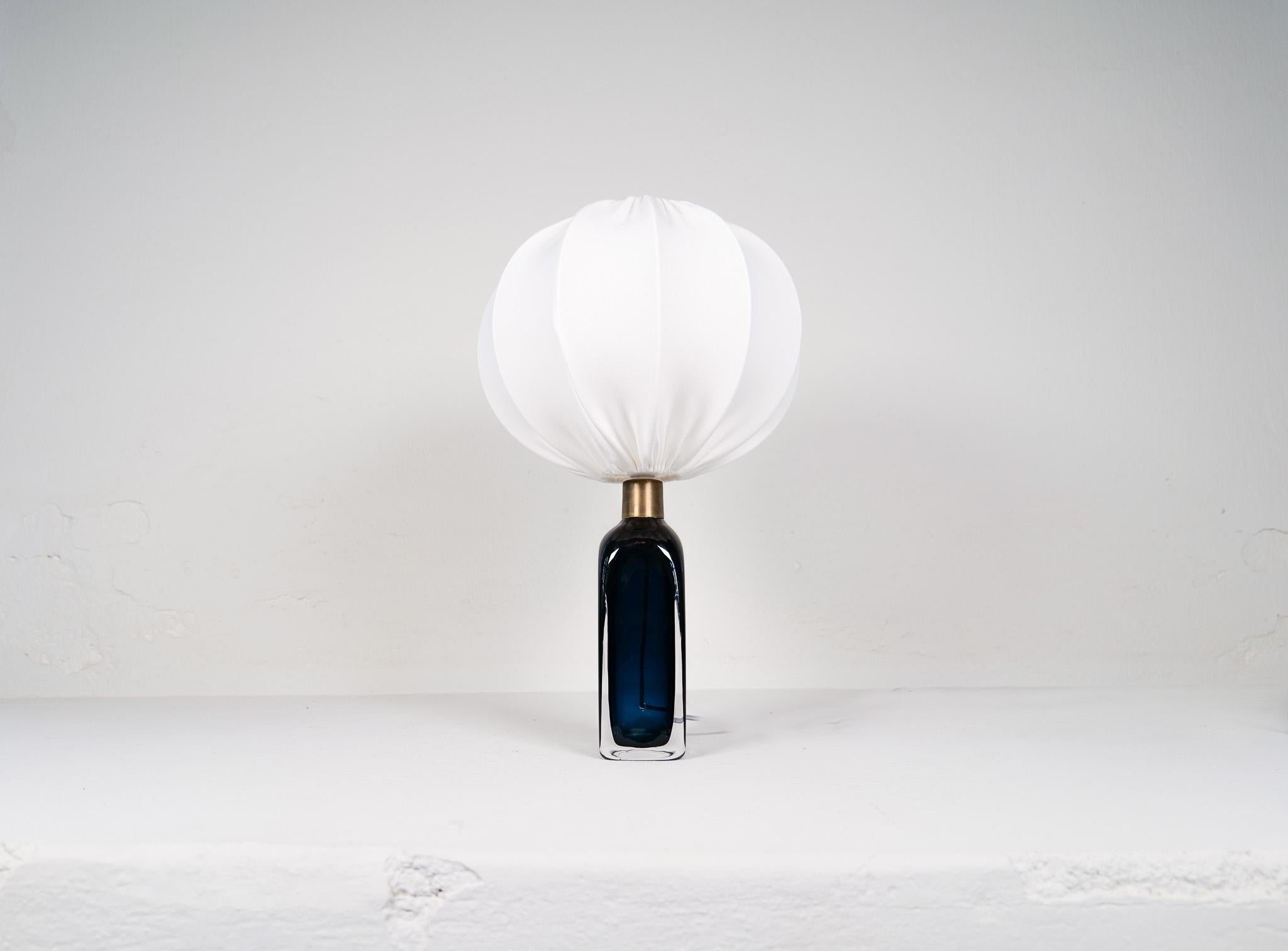 Table lamp in crystal, model RD1406 by Carl Fagerlund for Orrefors, Sweden.
The lamp have a stunning blue color with brass details. Together with the new cotton shades this lamp gives a fresh modern look. 

Good vintage condition. 

Dimensions : H