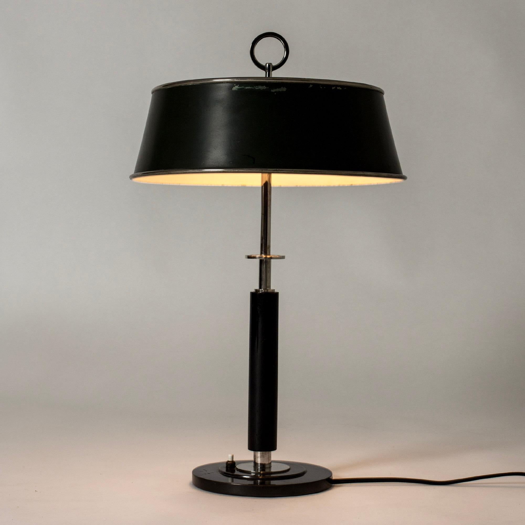 Élégante lampe de table fonctionnaliste d'Erik Tidstrand, en métal avec un abat-jour laqué vert foncé. Poignée et base noires, détails décoratifs en métal blanc dans un design graphique.
