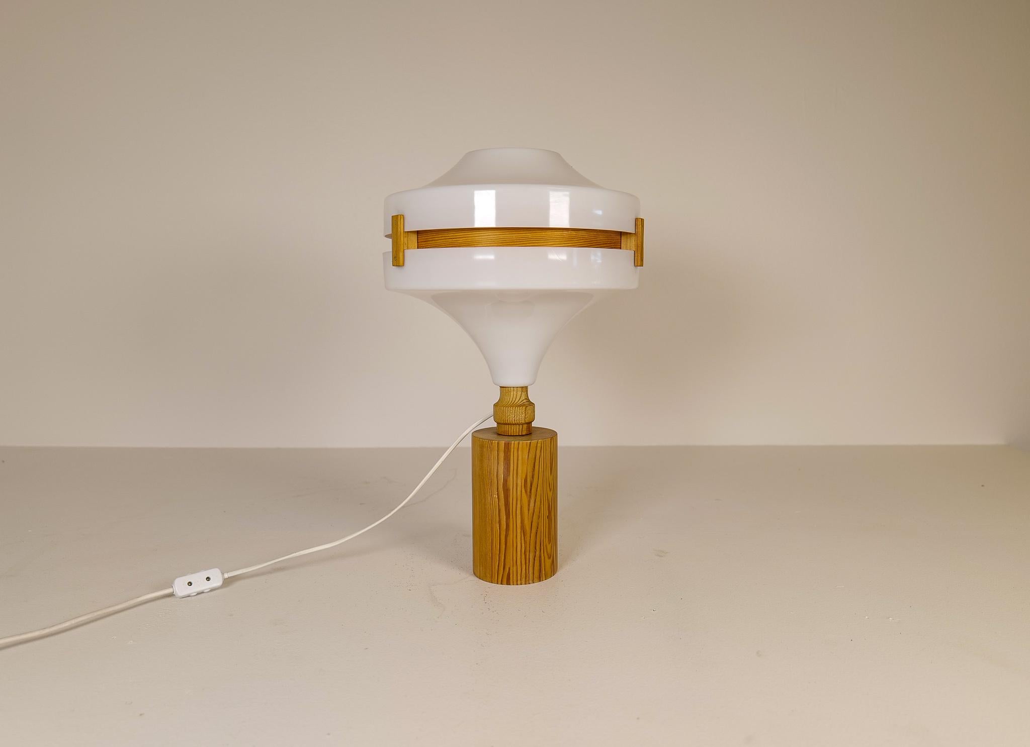 A nice-looking table lamp made with rounded solid pine, with and acrylic white top. The inside of the shade is gifted with rounded thin pine. 
Made in Sweden during the late 60s or early 70s, this lamp gives a nice edition to any home. 

Good