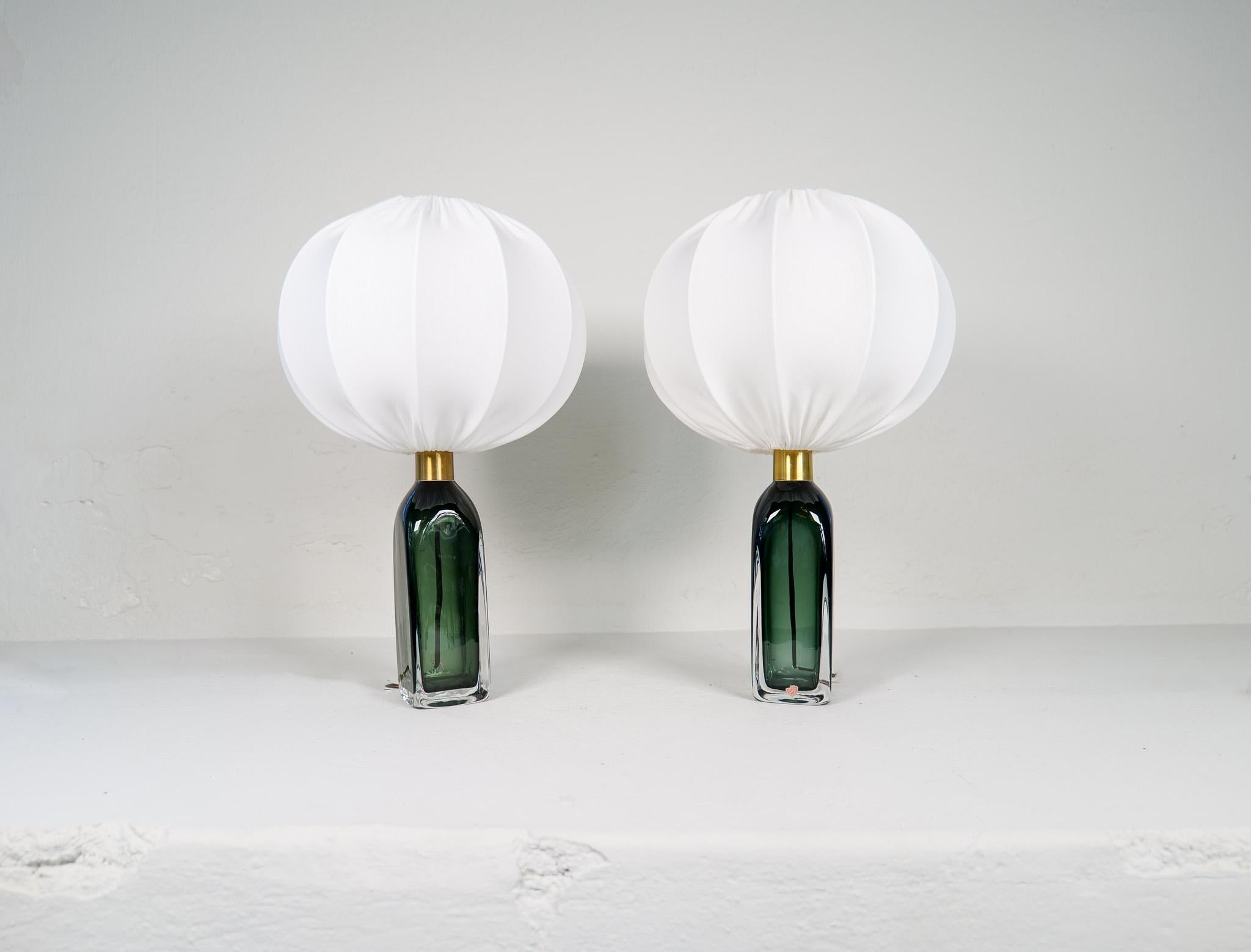 Table lamp in crystal, model RD1406 by Carl Fagerlund for Orrefors, Sweden.
The lamps have a stunning green color with brass details. Together with the new cotton shades this lamp gives a fresh modern look. 

Good vintage condition. 

Measures: H 34