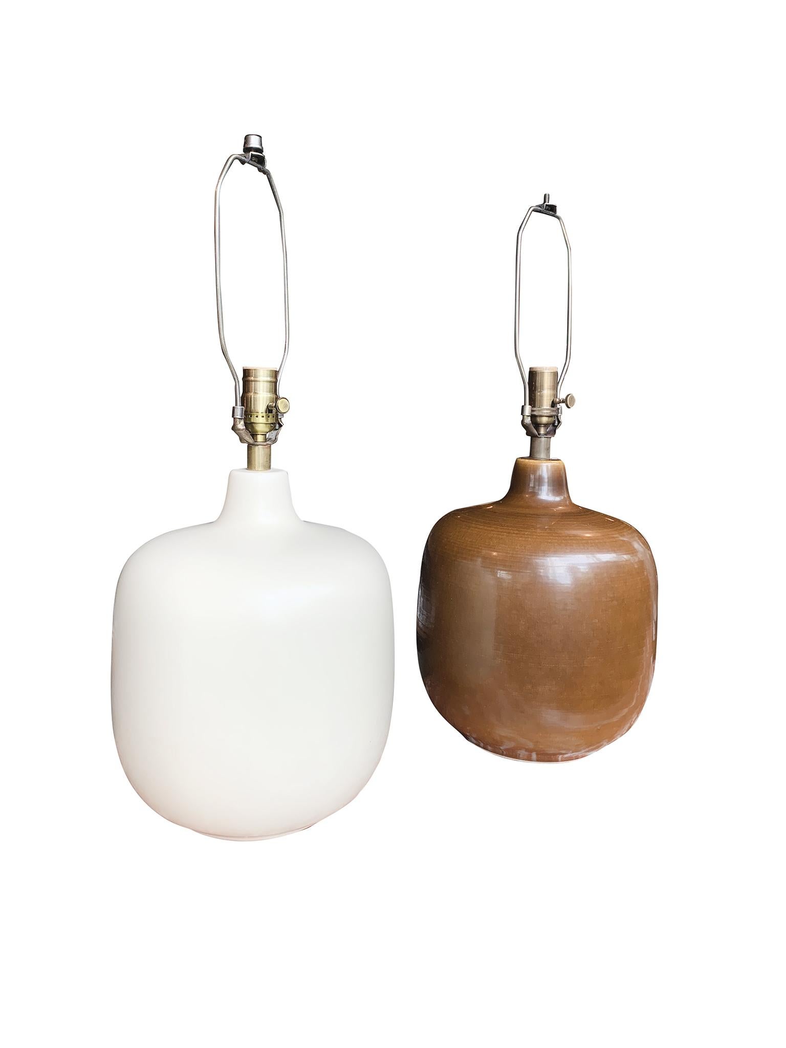 An exceptional set of 2 midcentury Danish Modern ceramic table lamps by Lotte and Gunnar Bostlund. The set is comprised of one lamp in a matte white and another lamp in an ocher yellow-brown glaze. Both lamps are elegantly understated with a round