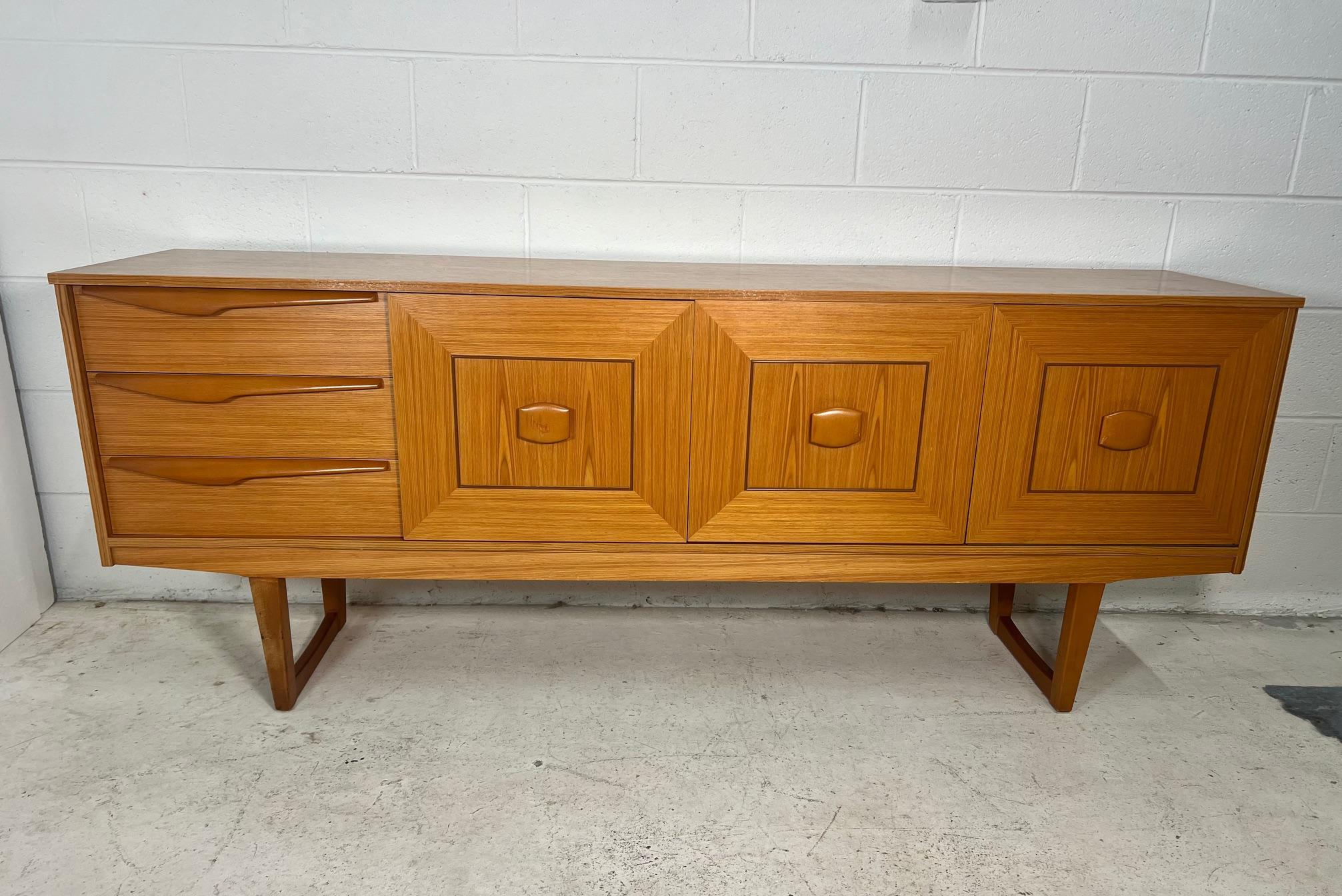 Outstanding teak credenza by Stateroom. Featuring 3 drawers on the left, drop down door bar on the right and a cabinet with removable shelves in the middle. Very good condition overall, some scratches on handles as shown in photos. Small stain on