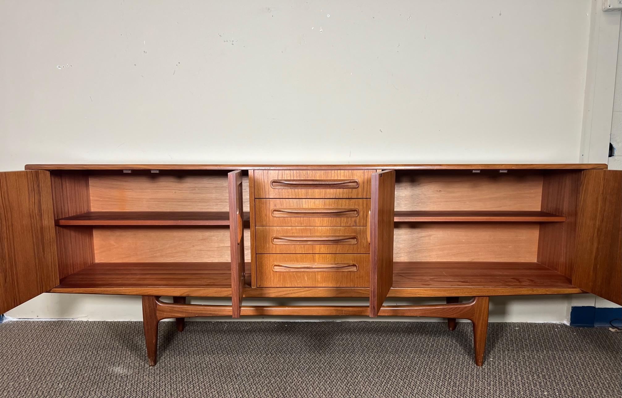Outstanding teak credenza by G Plan with original gray fabric with silverware dividers in the top drawer. Adjustable shelves. Very good condition. Drawers all open and close well. Some scratches inside drawers. Ring mark in right cabinet. Minor