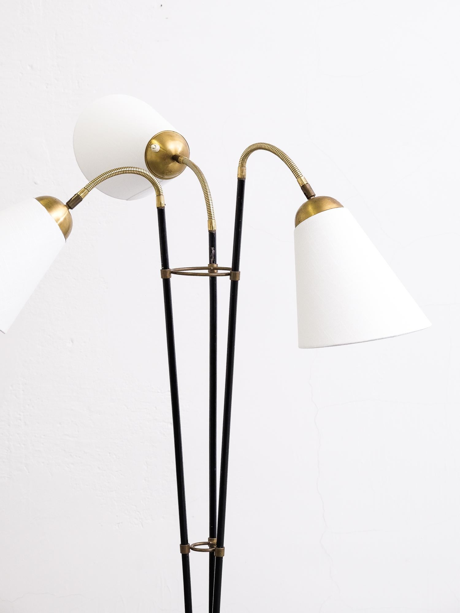 A black enamelled iron and brass three-arm floor lamp, with new offwhite fabric shades.
Manufactured in Sweden, 1950s.